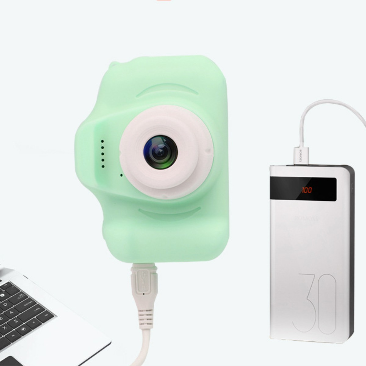 Minzgrüne Kamera, verbunden mit einer weißen Powerbank, weißem Kabel und Laptop.