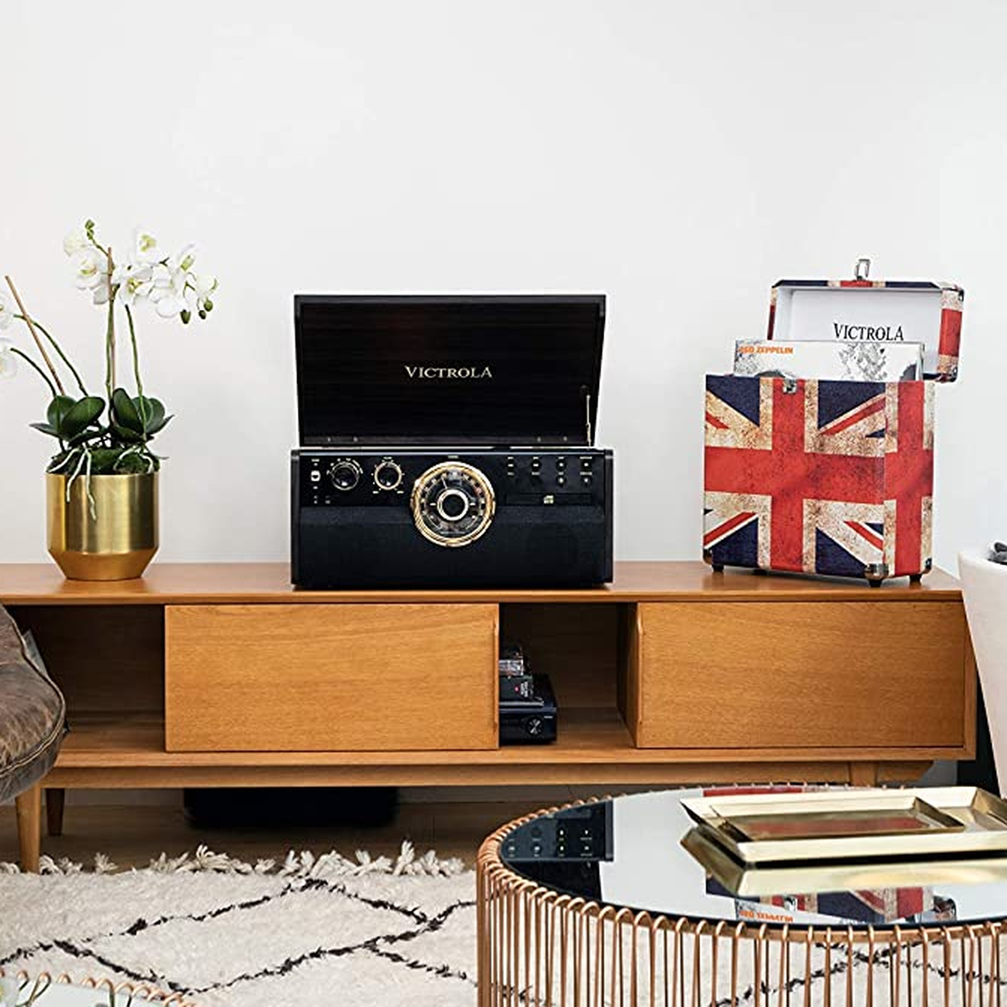 Sistema estéreo retro en mueble de madera con caja Union Jack, mesa espejo y planta.