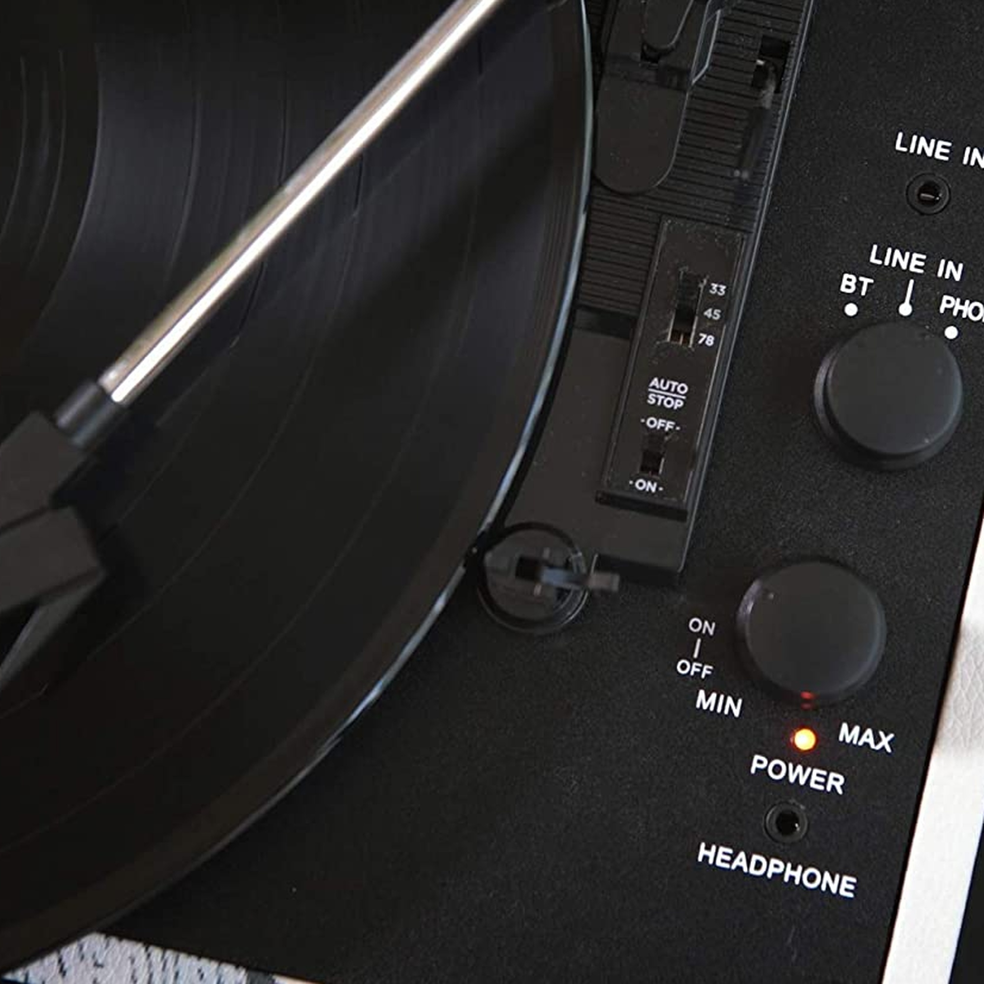 Primo piano di un giradischi con un disco in vinile nero e pulsanti di controllo.