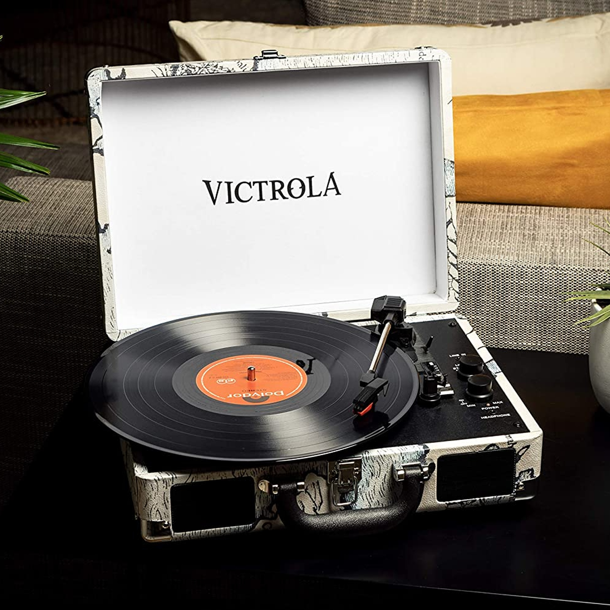 Tocadiscos Victrola abierto con un disco de vinilo negro. El tocadiscos está sobre una superficie oscura.