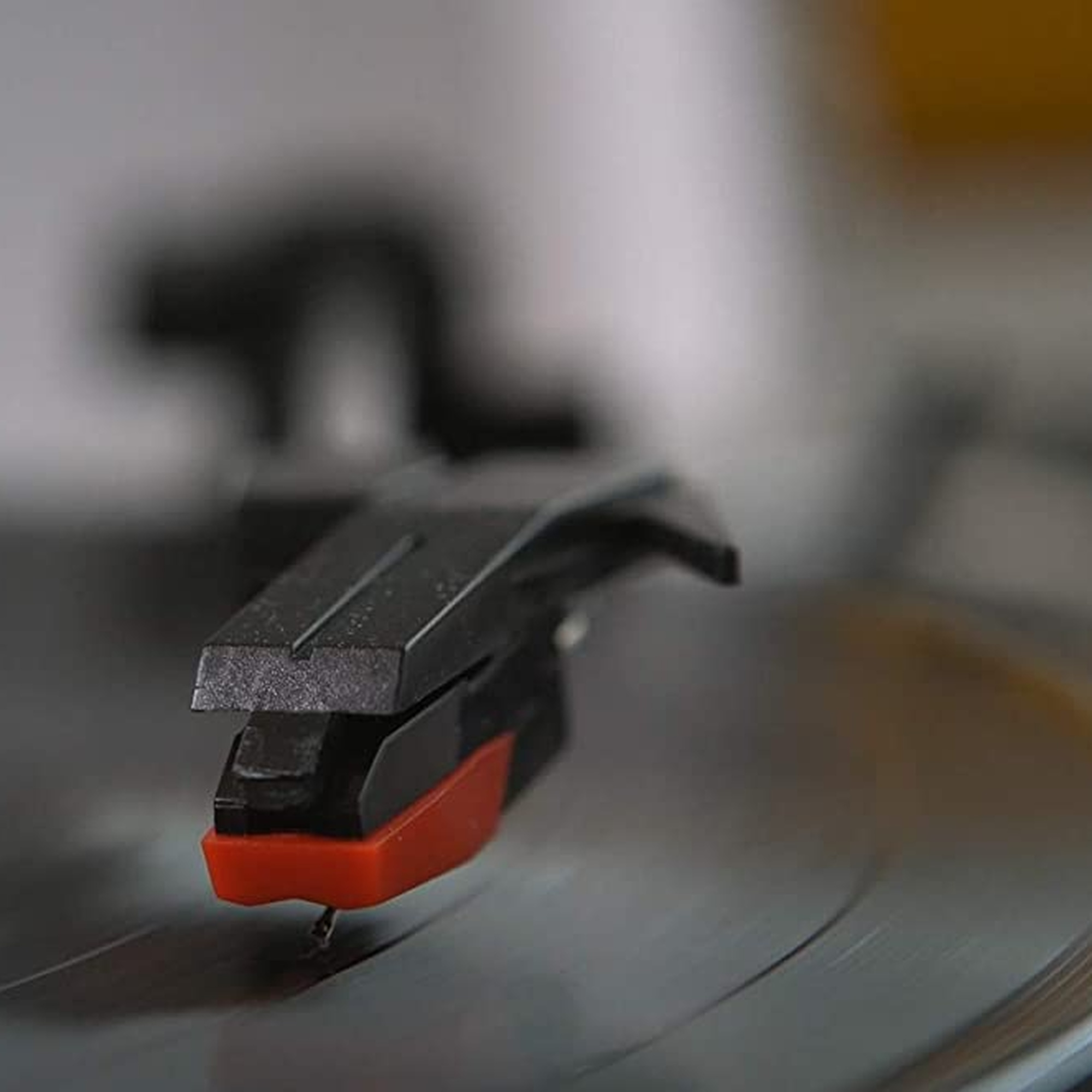 Primo piano della puntina di un giradischi su un disco in vinile. Puntina e braccio tonale rosso e nero.
