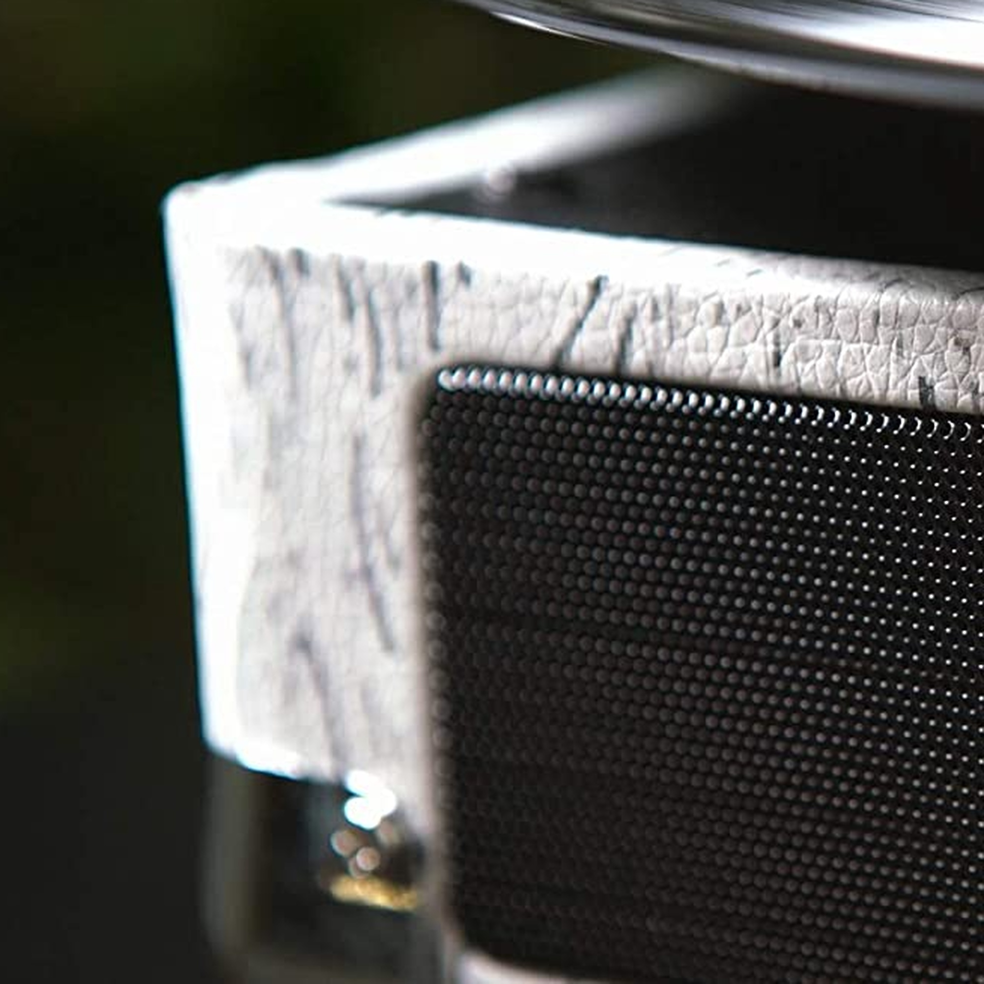 Primer plano de un altavoz con superficie texturizada blanca y negra.