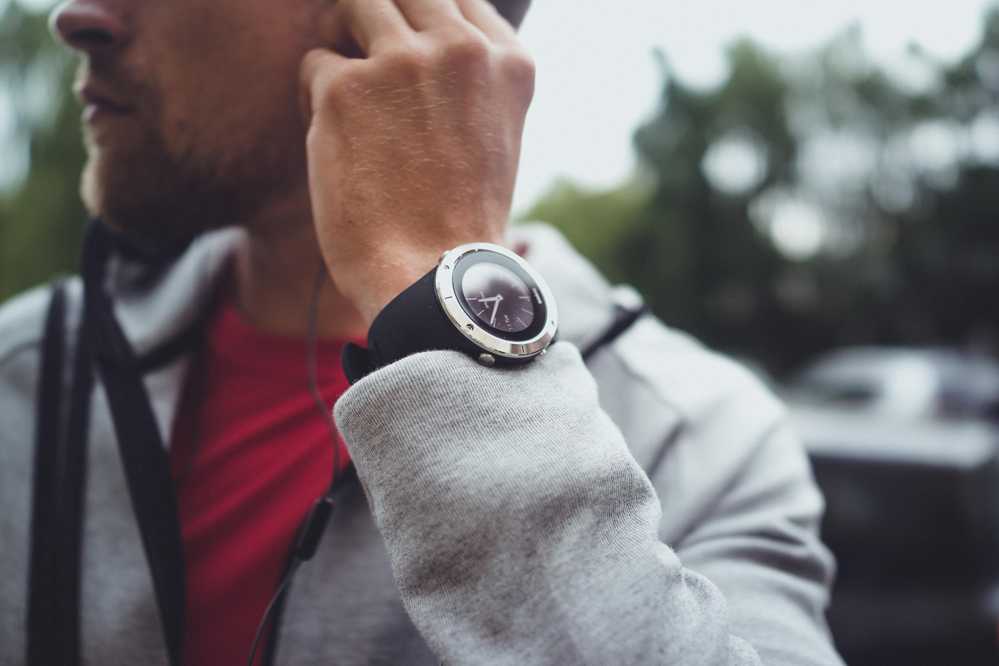 Ein Mann, der eine Uhr am Handgelenk trägt und ein Telefon an sein Ohr hält.