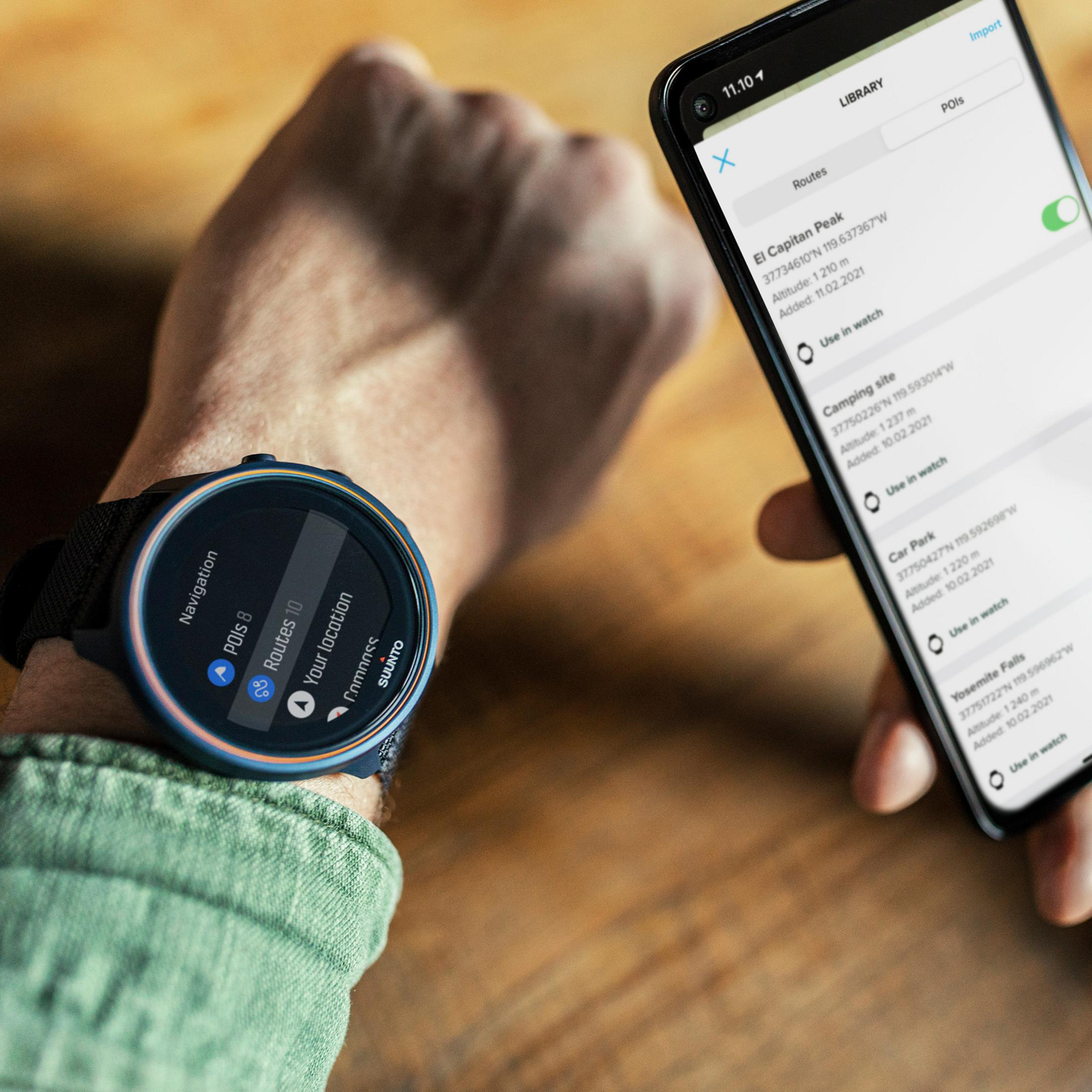 Osoba nosząca zegarek Suunto. Zegarek pokazuje dane nawigacyjne. Widoczny telefon.