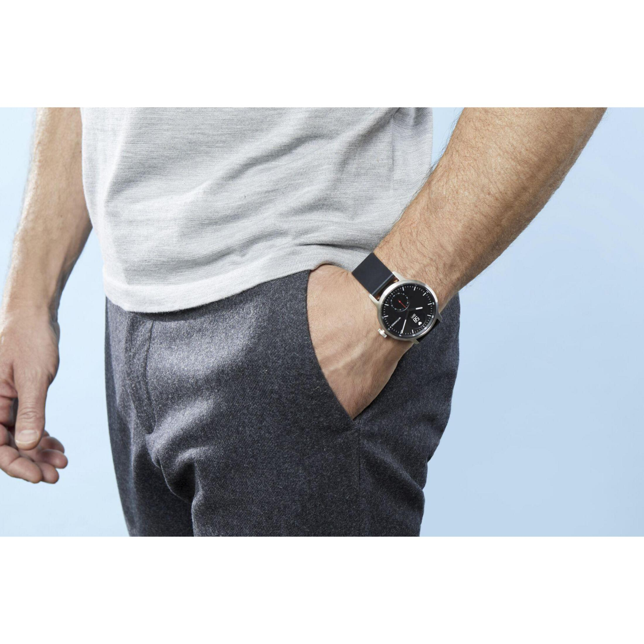 Eine Person mit Uhr am Handgelenk, die Hand in der Hosentasche.