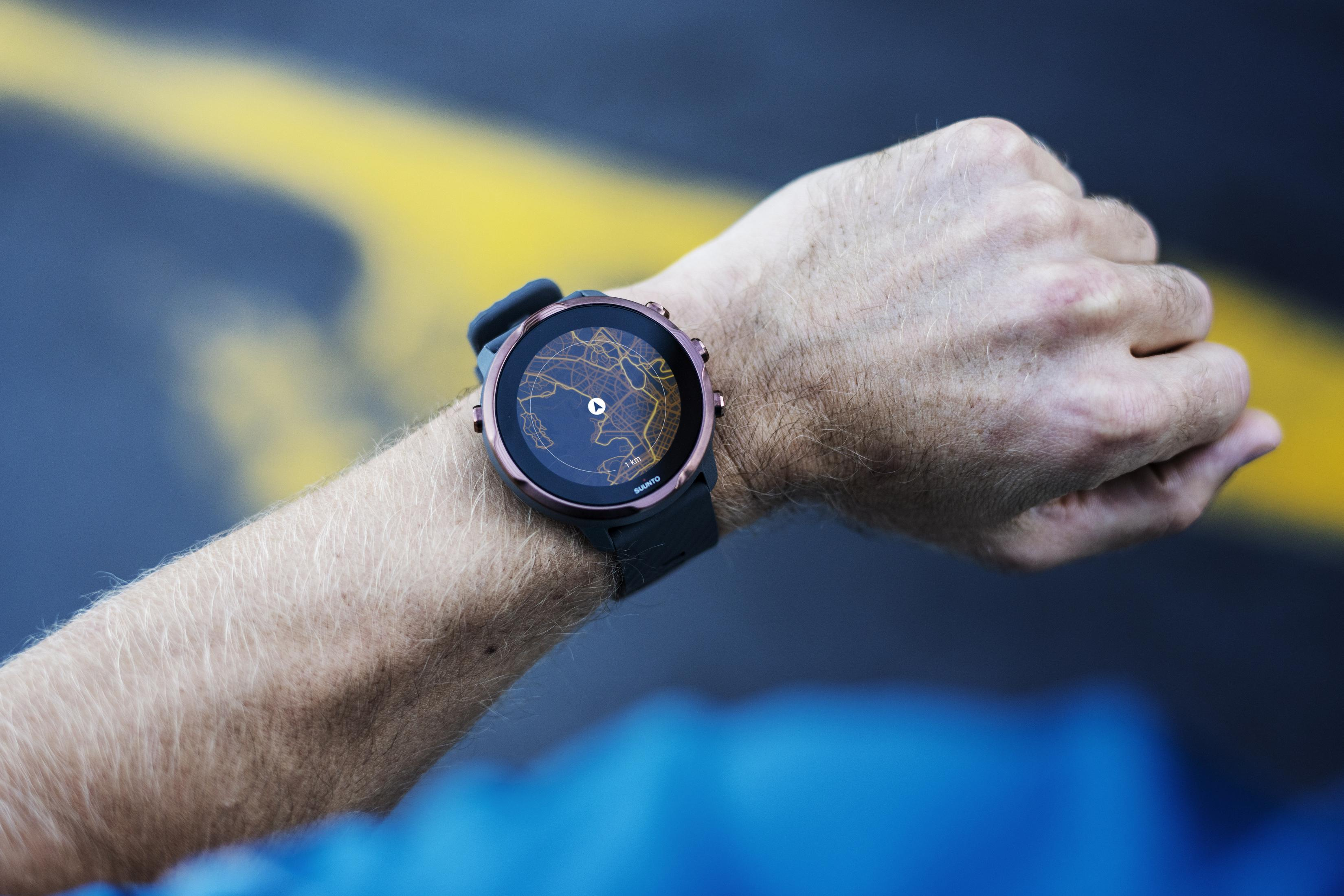 Hand einer Person, die eine Sportuhr hält. Die Uhr zeigt eine Karte auf einem kreisförmigen Bildschirm.