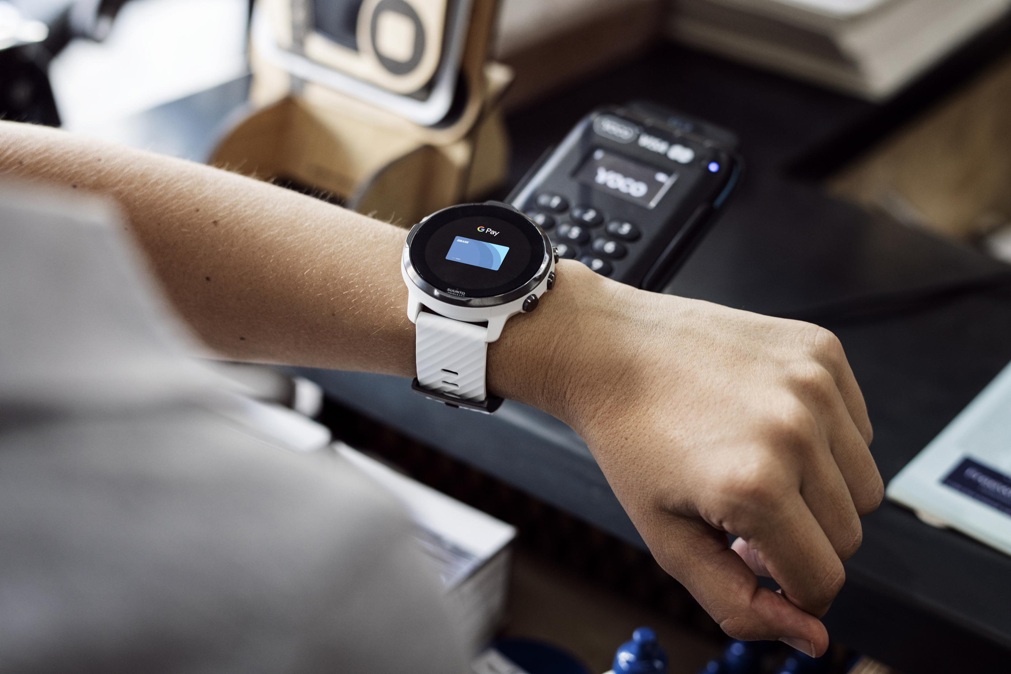 Person trägt weiße Uhr mit gekrümmtem Bildschirm, zeigt G Pay, beim Bezahlen.