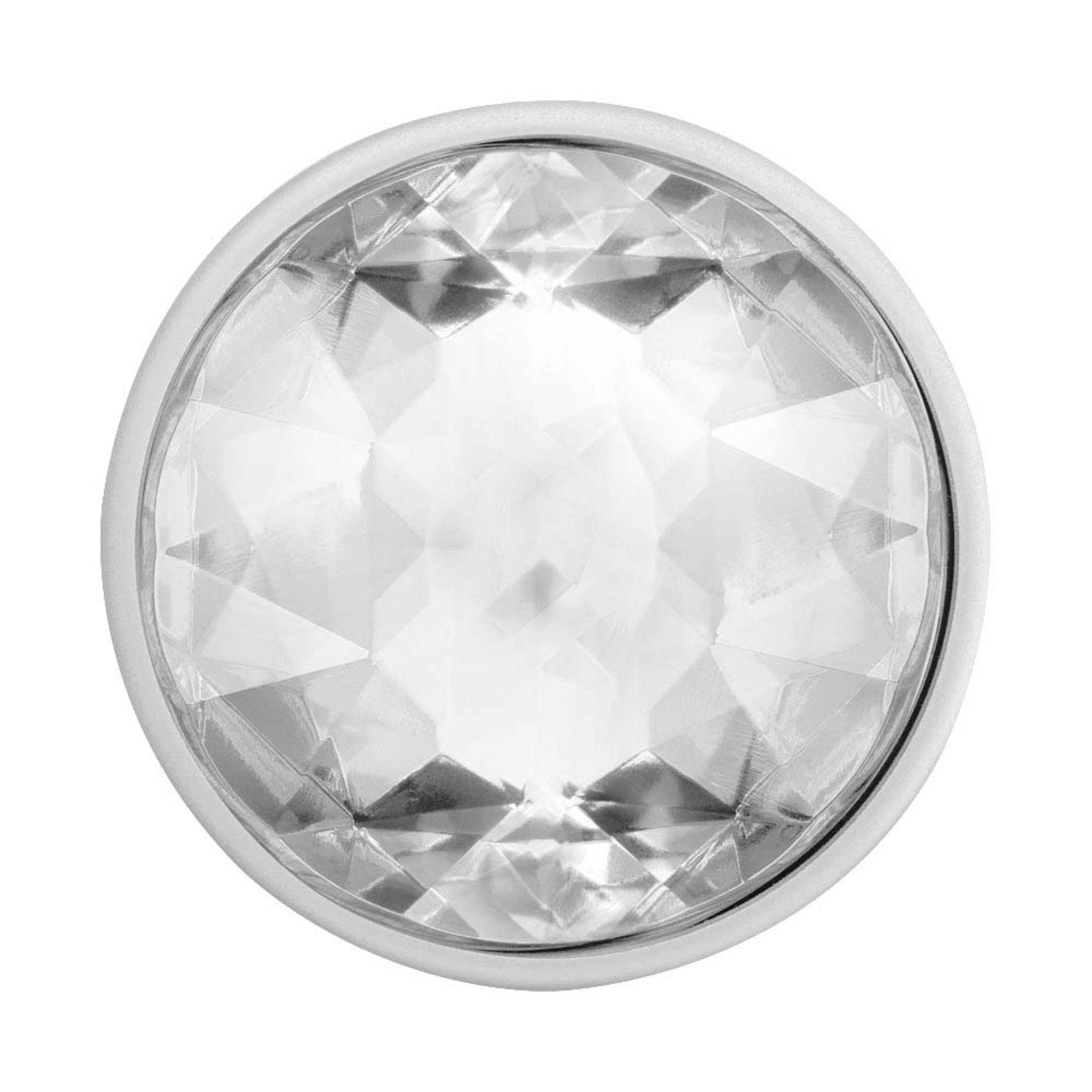 Un objeto transparente y redondo, similar a un diamante, engastado en un anillo de plata, aislado sobre fondo blanco.