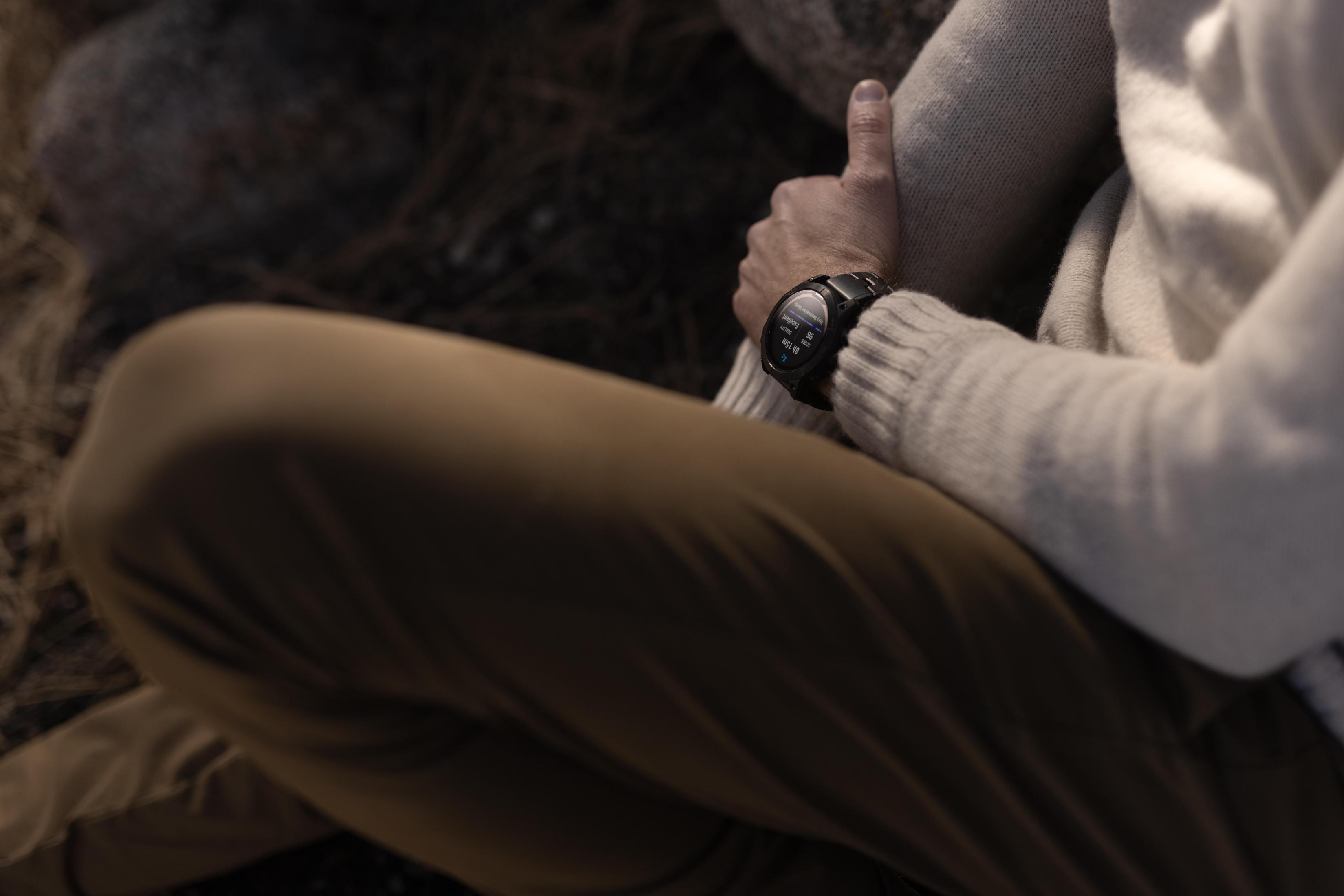 Een persoon die een horloge om de pols draagt, met een bruine broek en een witte trui.