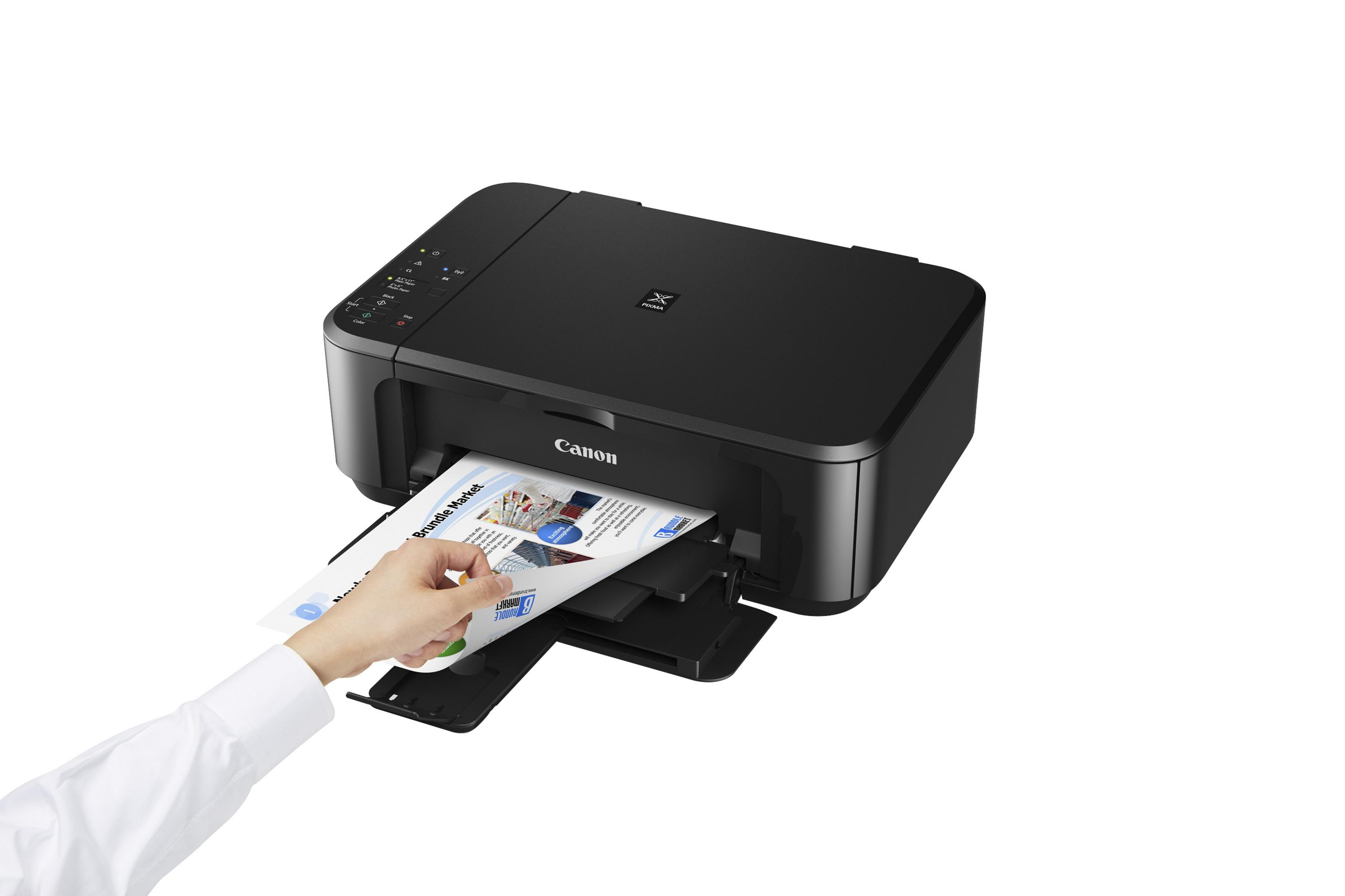 Czarna drukarka Canon drukująca dokument. Ręka wyciąga wydrukowaną kartkę.