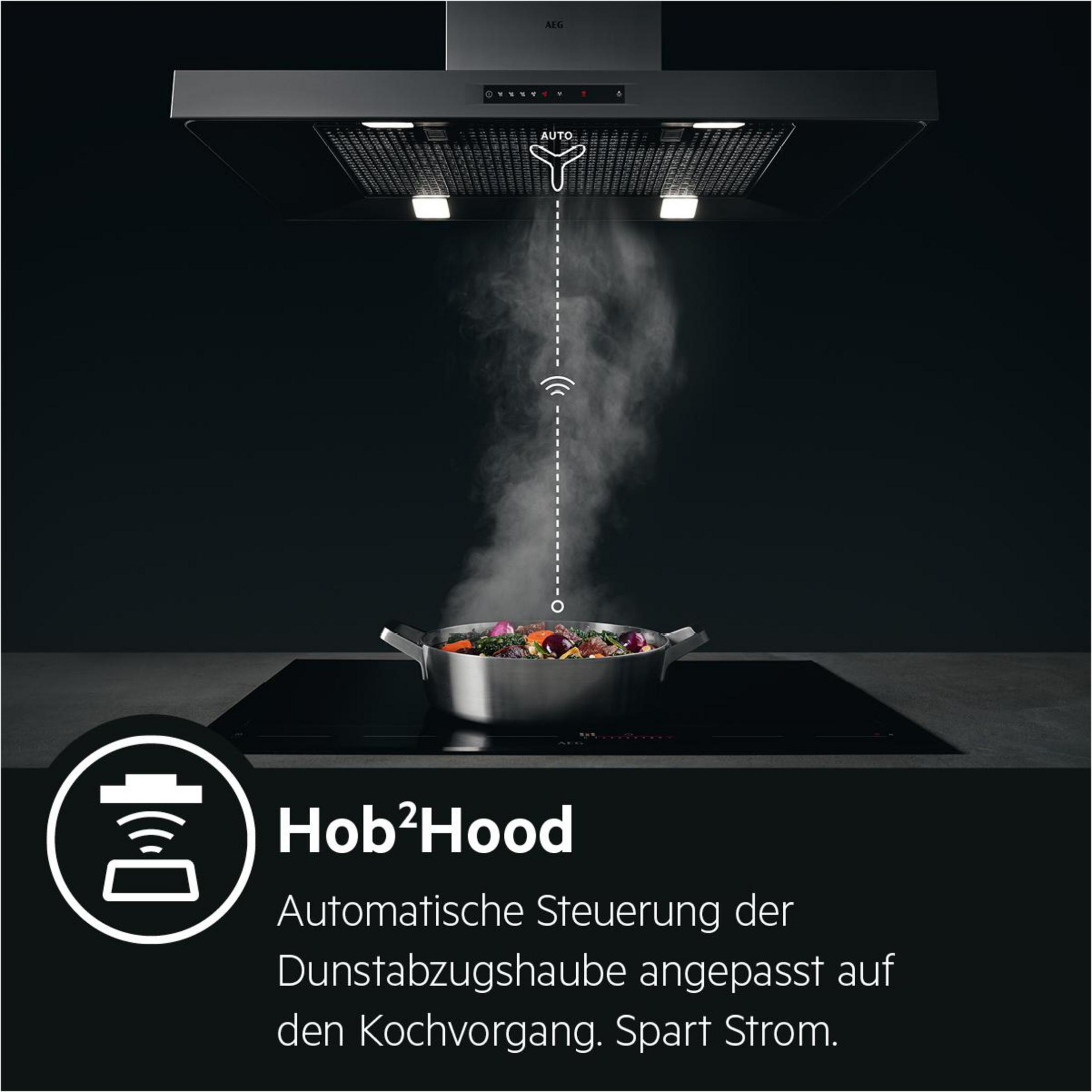 Schwarze Dunstabzugshaube mit Dampf über einem Topf auf schwarzem Kochfeld.