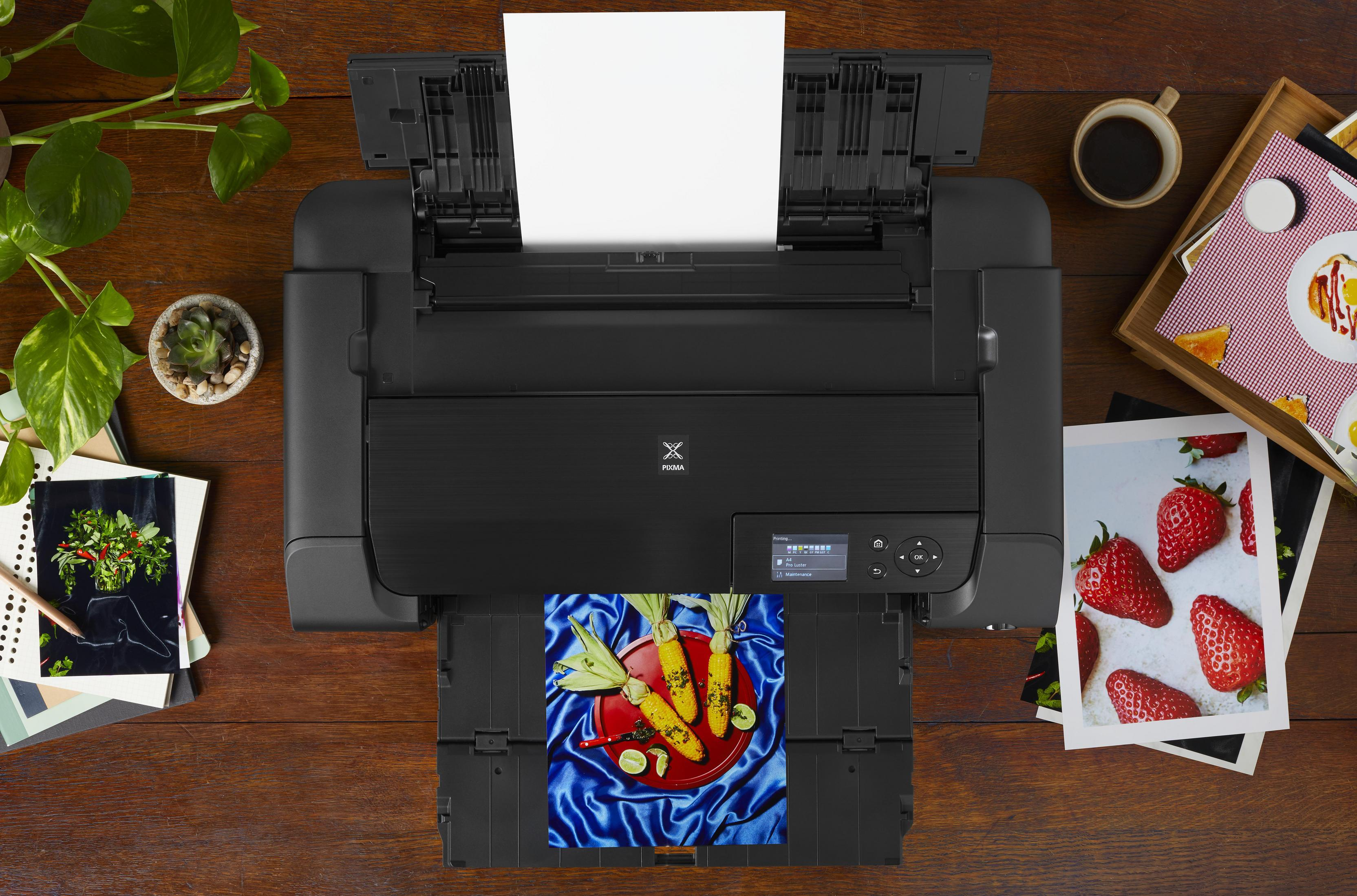 Stampante che stampa un'immagine colorata. Intorno alla stampante ci sono foto e oggetti.