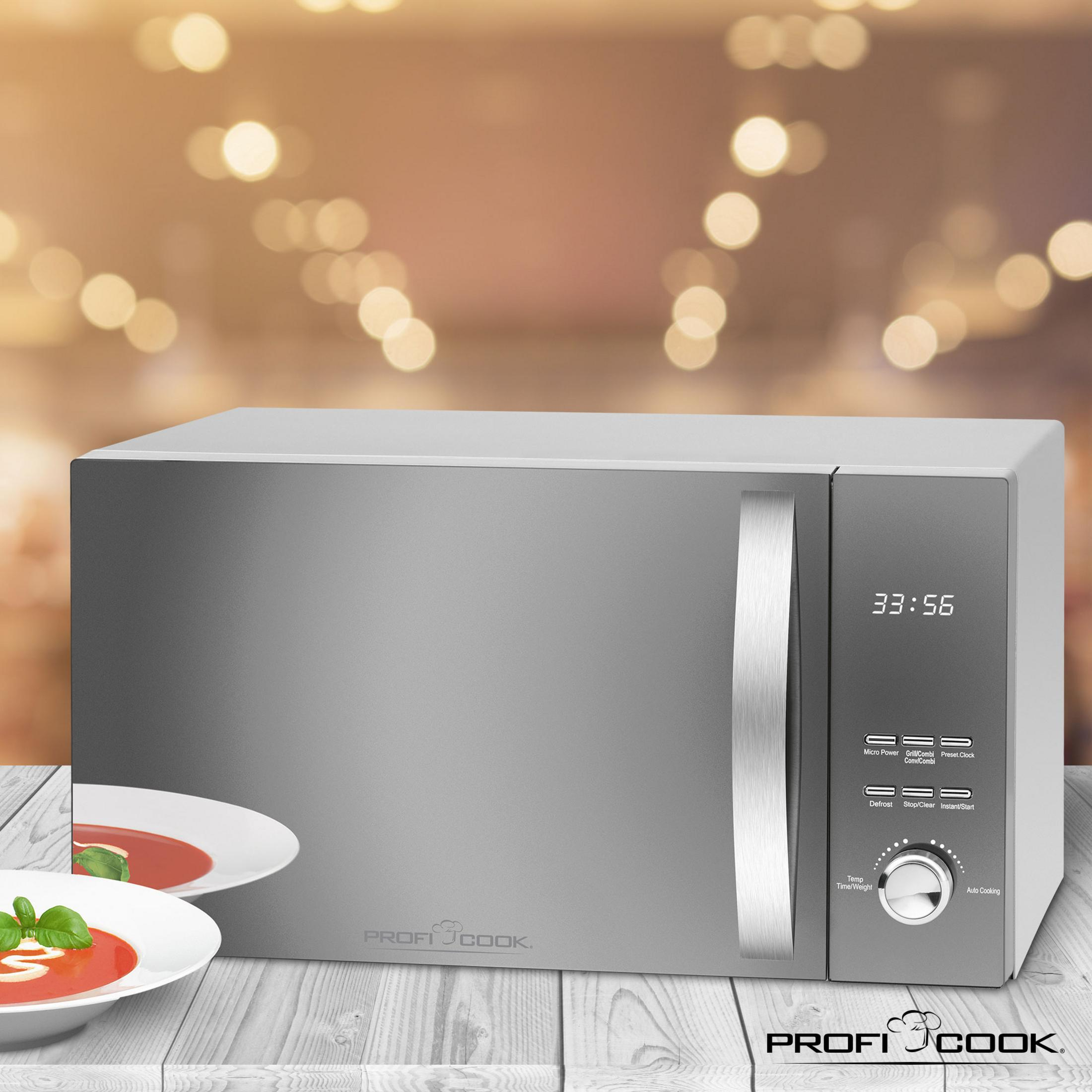 Srebrna kuchenka mikrofalowa z wyświetlaczem cyfrowym, czas 33:56, i dwie białe miski z zupą po lewej.