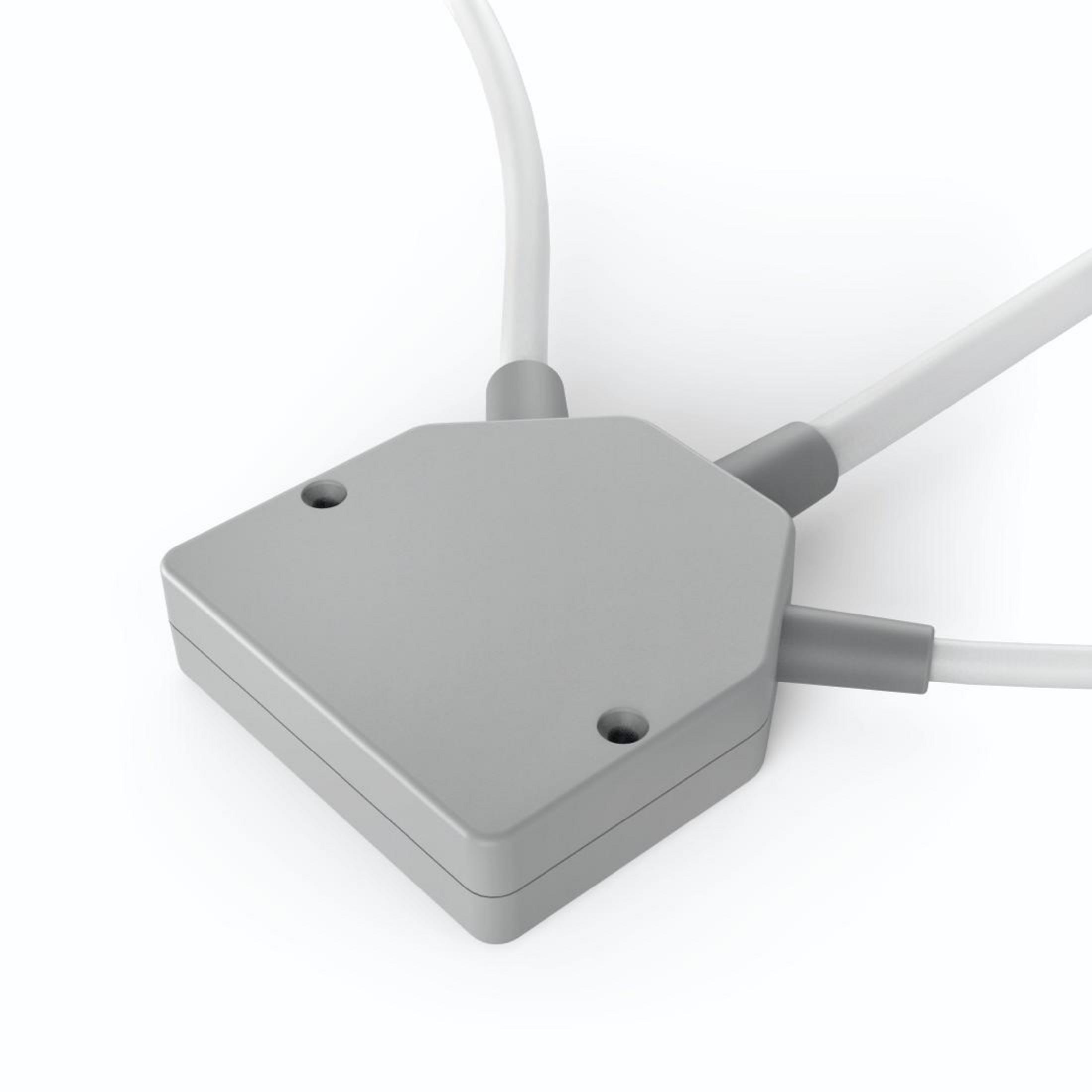 Graue Elektro-Verteilerdose mit drei weißen Drähten, die von ihr ausgehen, auf weißer Oberfläche.