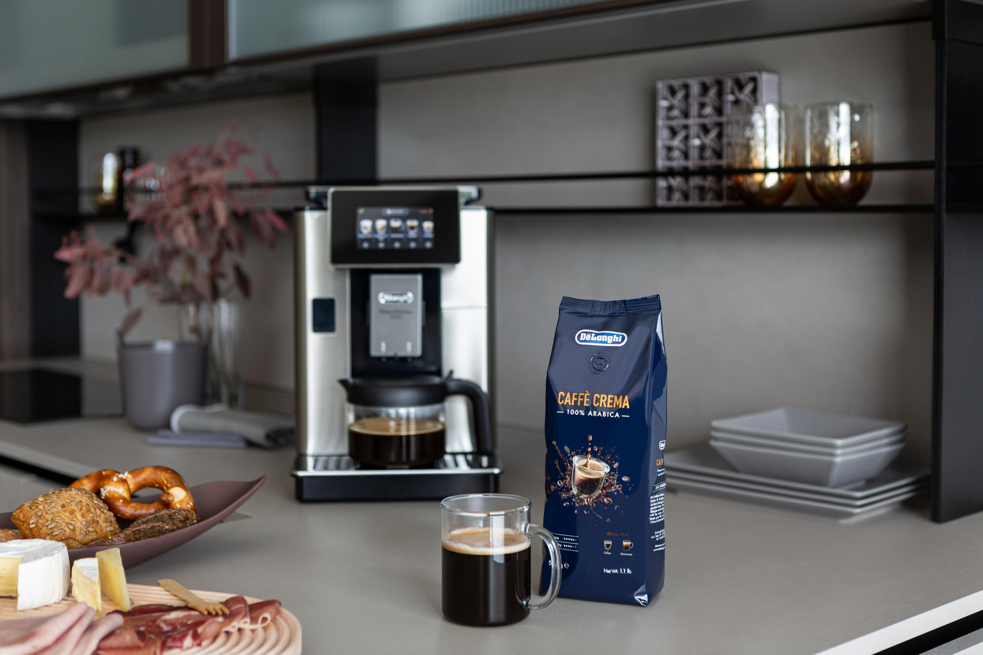 Küchenszene mit Kaffeemaschine, Kaffee und einem Beutel Kaffeebohnen auf der Arbeitsplatte.