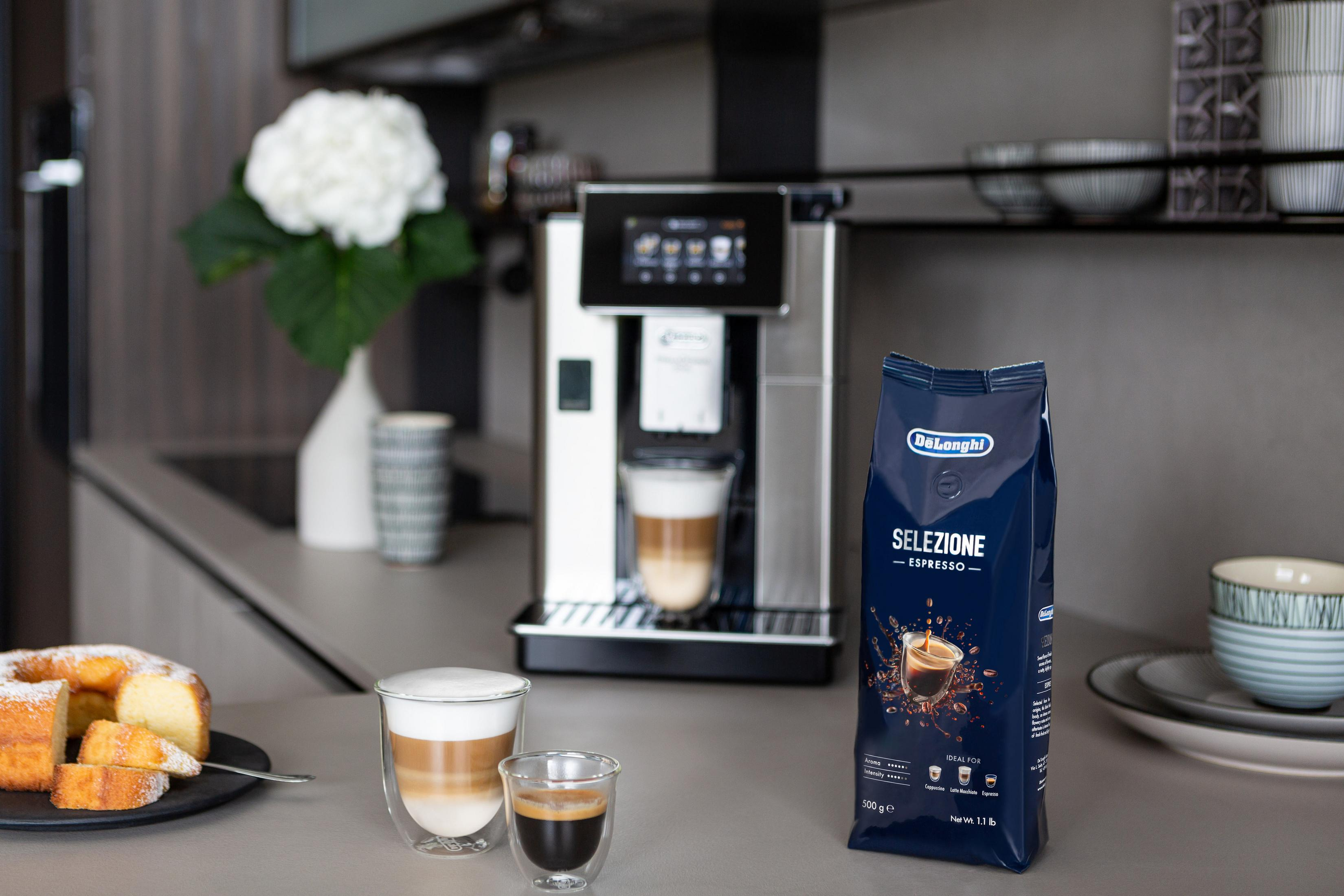 Una macchina per caffè espresso De'Longhi con un bicchiere di latte macchiato e un espresso.