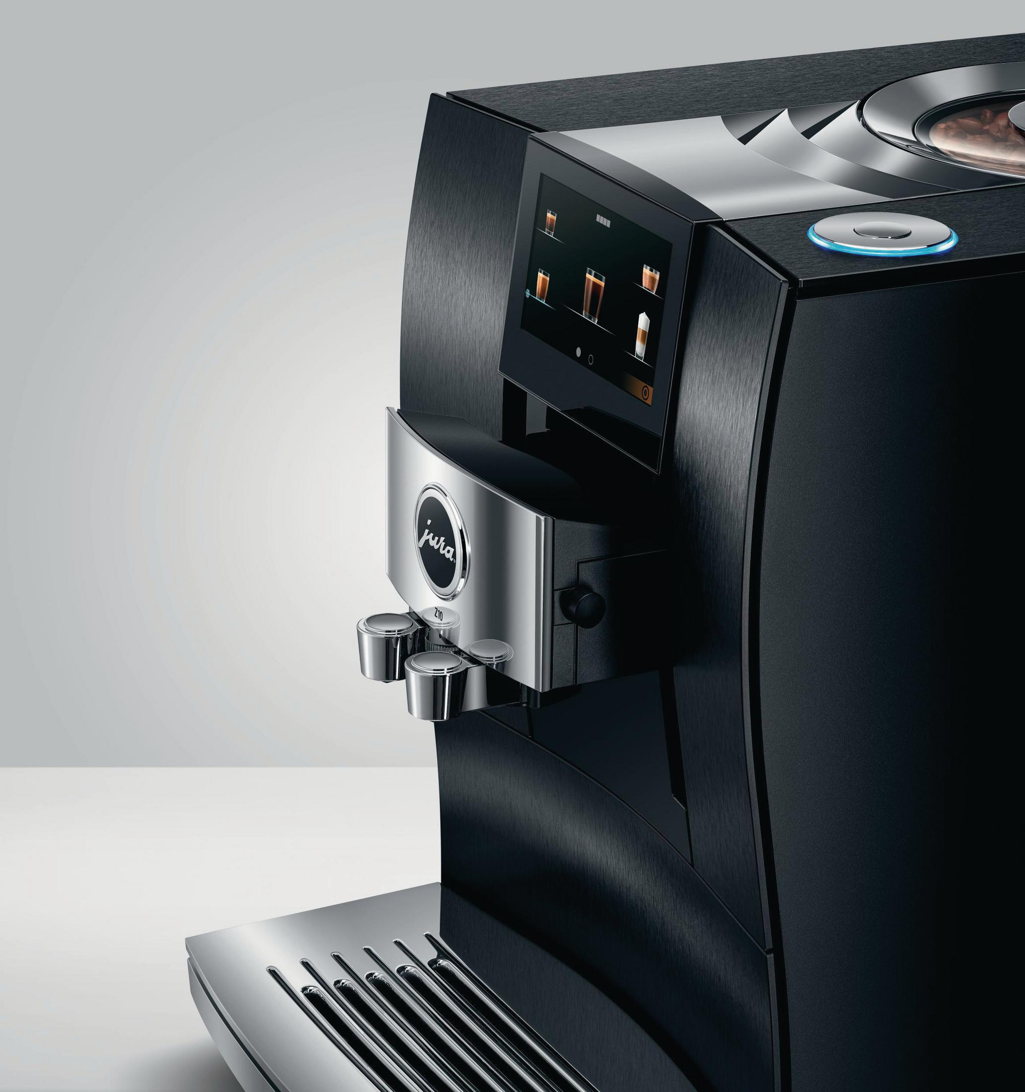 Czarny ekspres do kawy z ekranem dotykowym i srebrnymi detalami. Na dole dwie filiżanki z kawą.