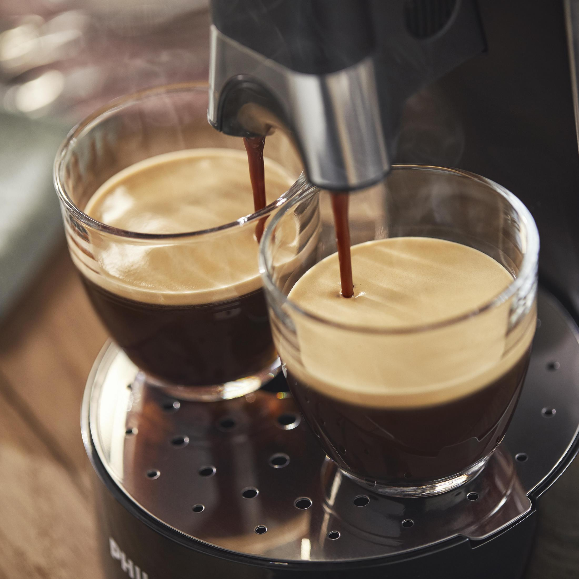 Espresso wird in zwei klare Gläser gegossen, wobei Crema- und Kaffeeschichten hervorgehoben werden.