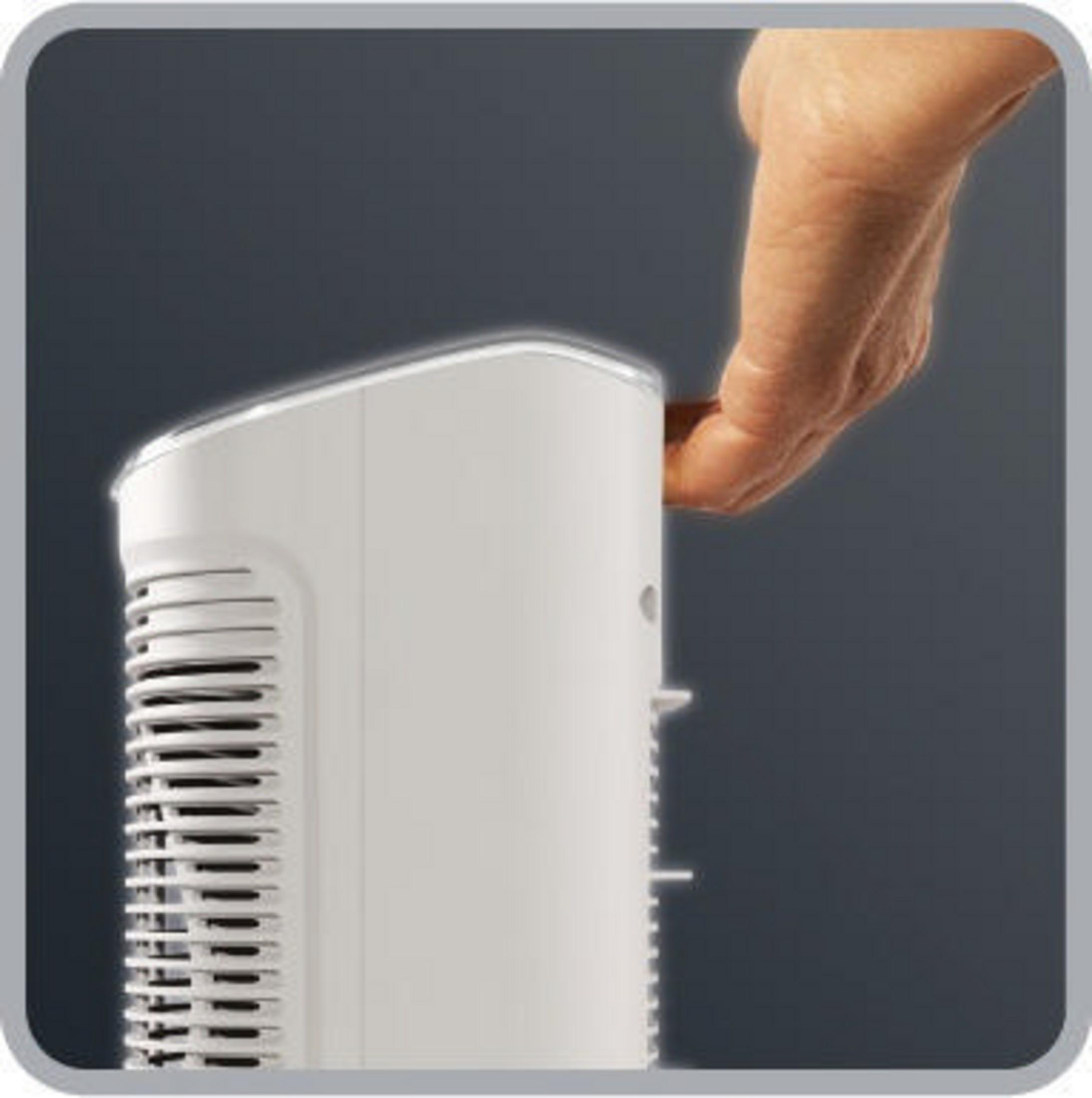 Mano extendiéndose hacia un electrodoméstico blanco. El electrodoméstico es blanco con fondo gris oscuro.