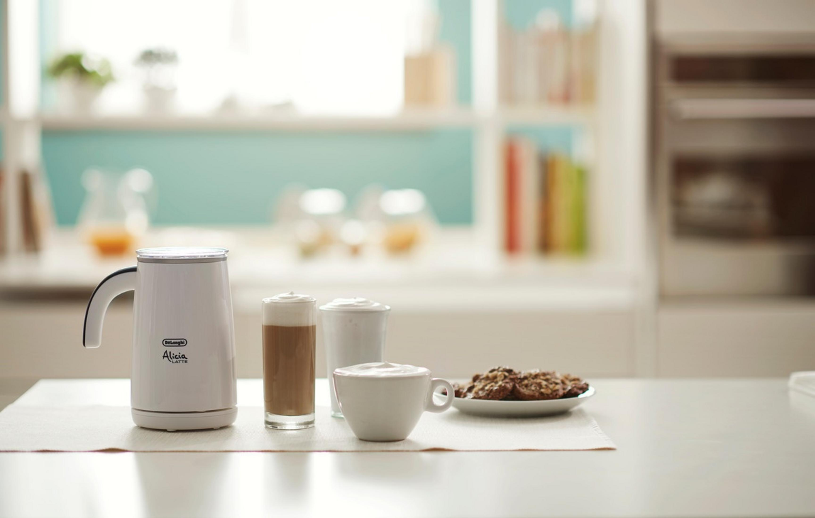Spieniacz do mleka DeLonghi z kawą, ciasteczkami i dwoma filiżankami.