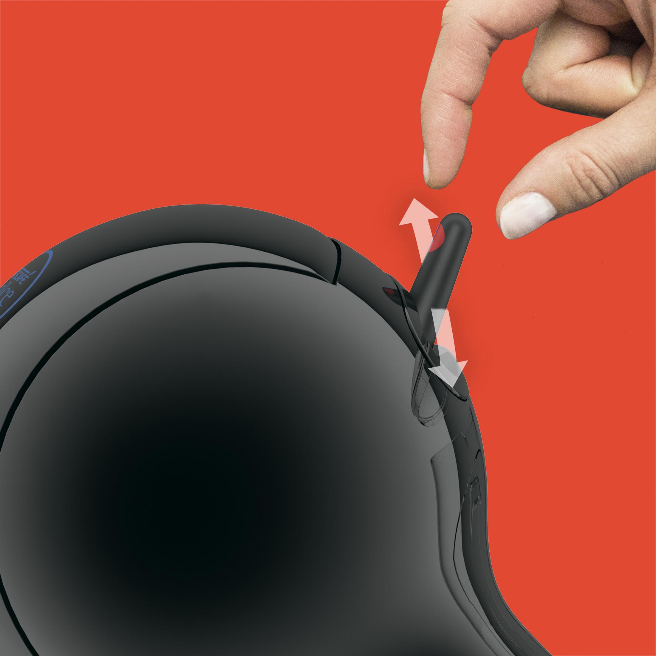 Ręka naciska czarny przycisk na czarnym urządzeniu. Czerwone tło z tyłu.