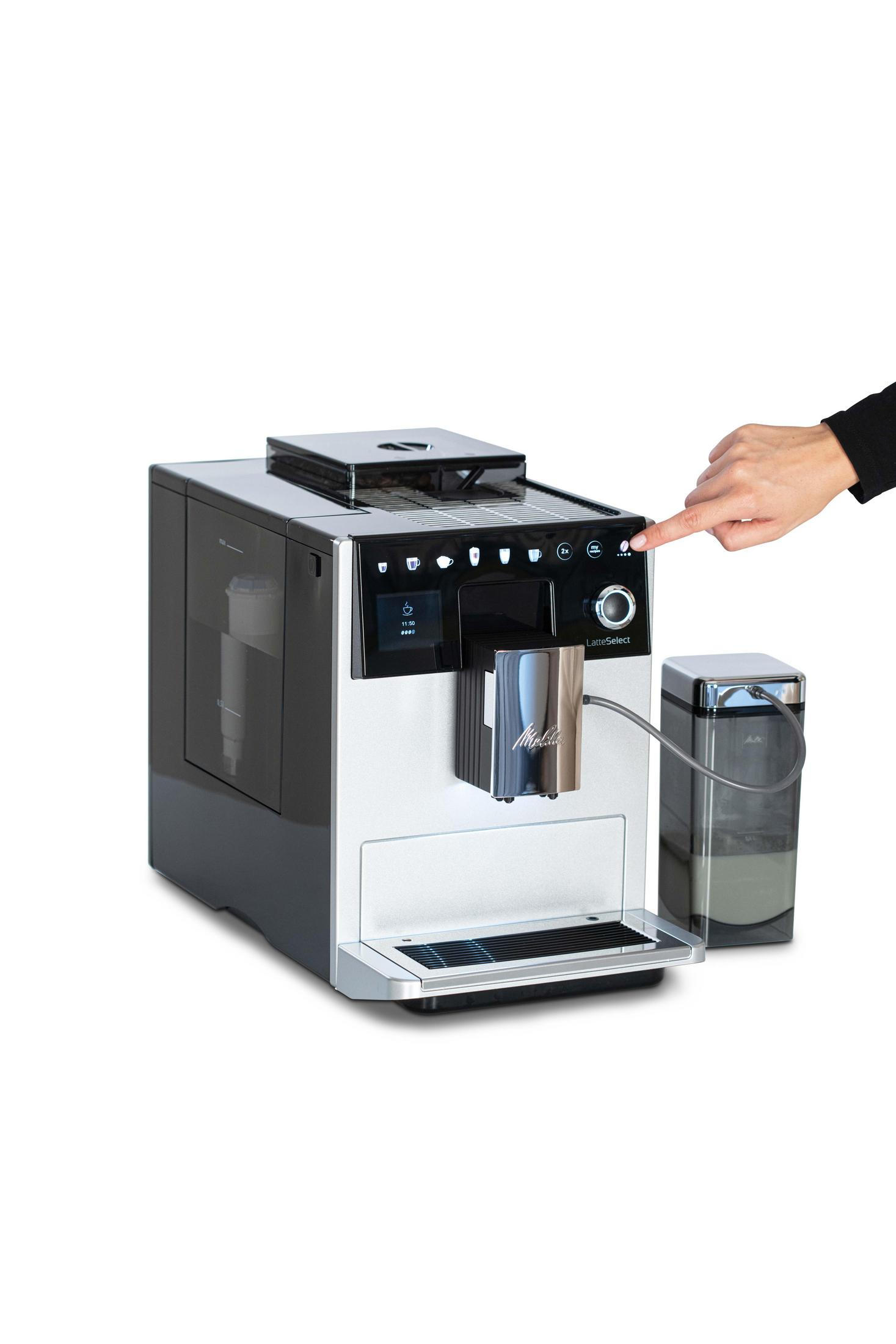 Der Finger einer Person drückt die Einschalttaste einer Melitta-Kaffeemaschine mit einem angrenzenden Wasserbehälter.