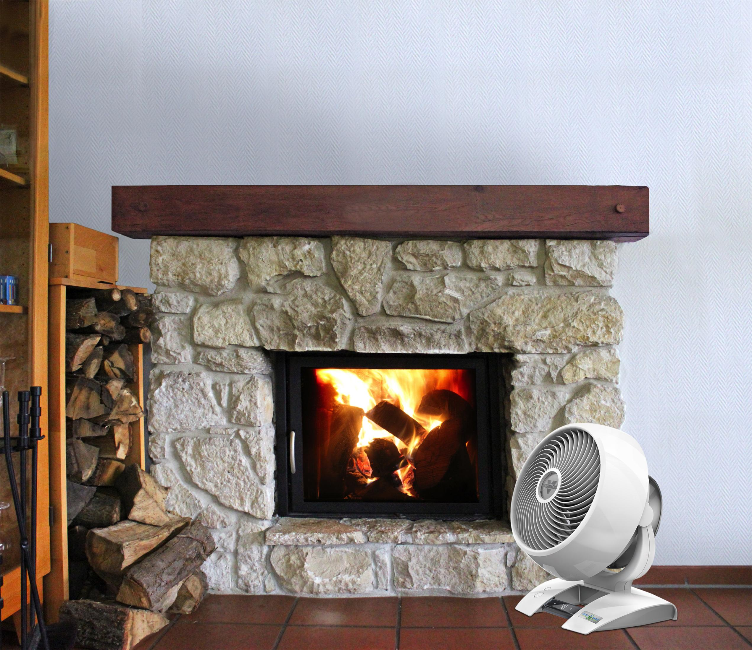 Kominek z płonącym ogniem. Biały wentylator z przodu. Stos drewna i półka po lewej.
