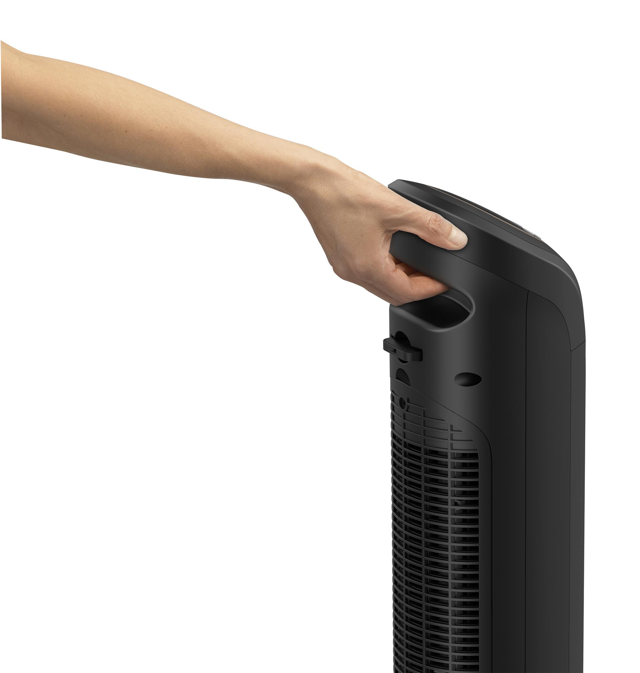 Dłoń trzymająca uchwyt czarnego wentylatora wieżowego, pokazująca tylny panel i design.