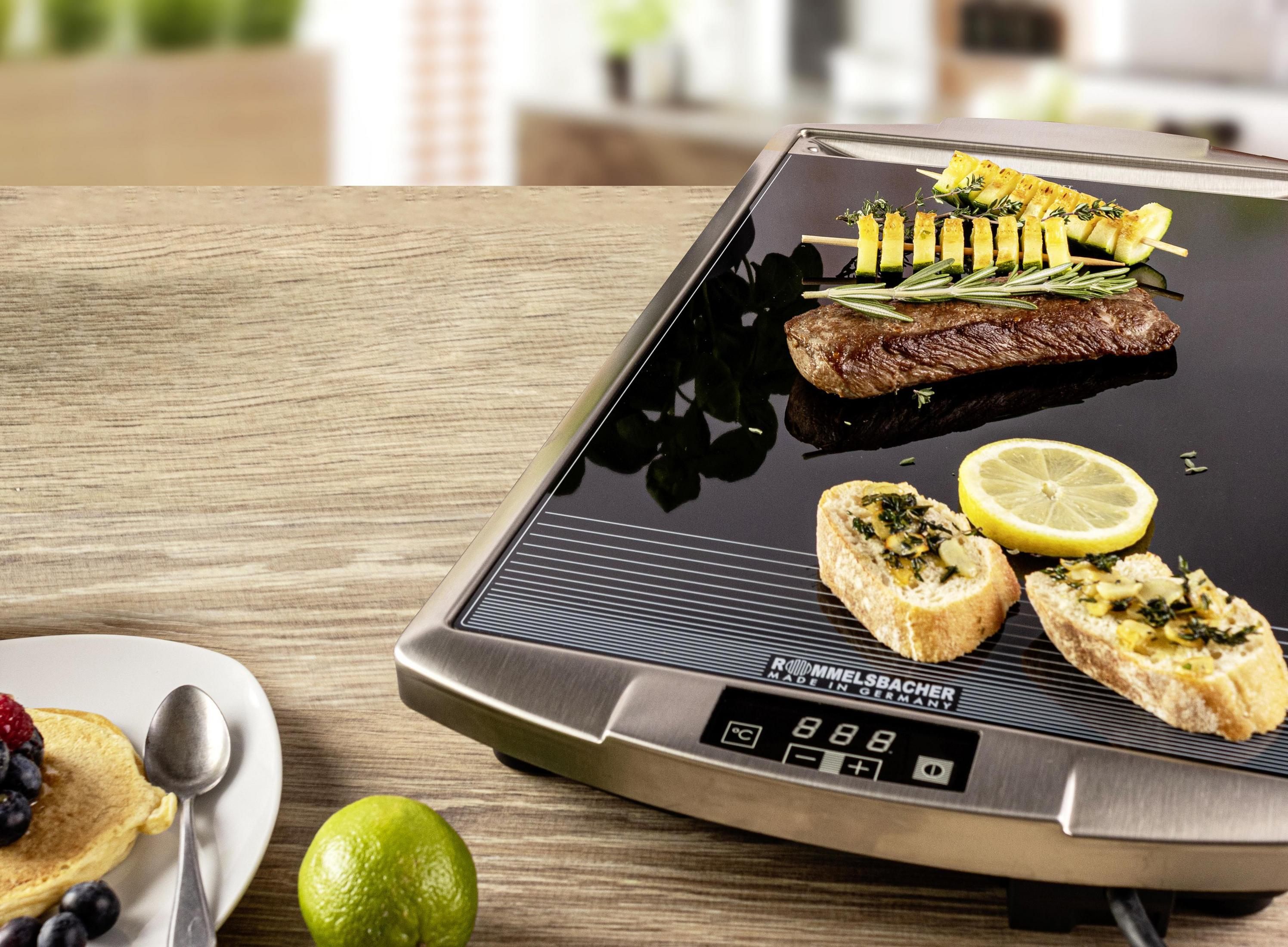 Superficie de cocción con bistec, brochetas y pan. Limón y lima. Mesa de madera.