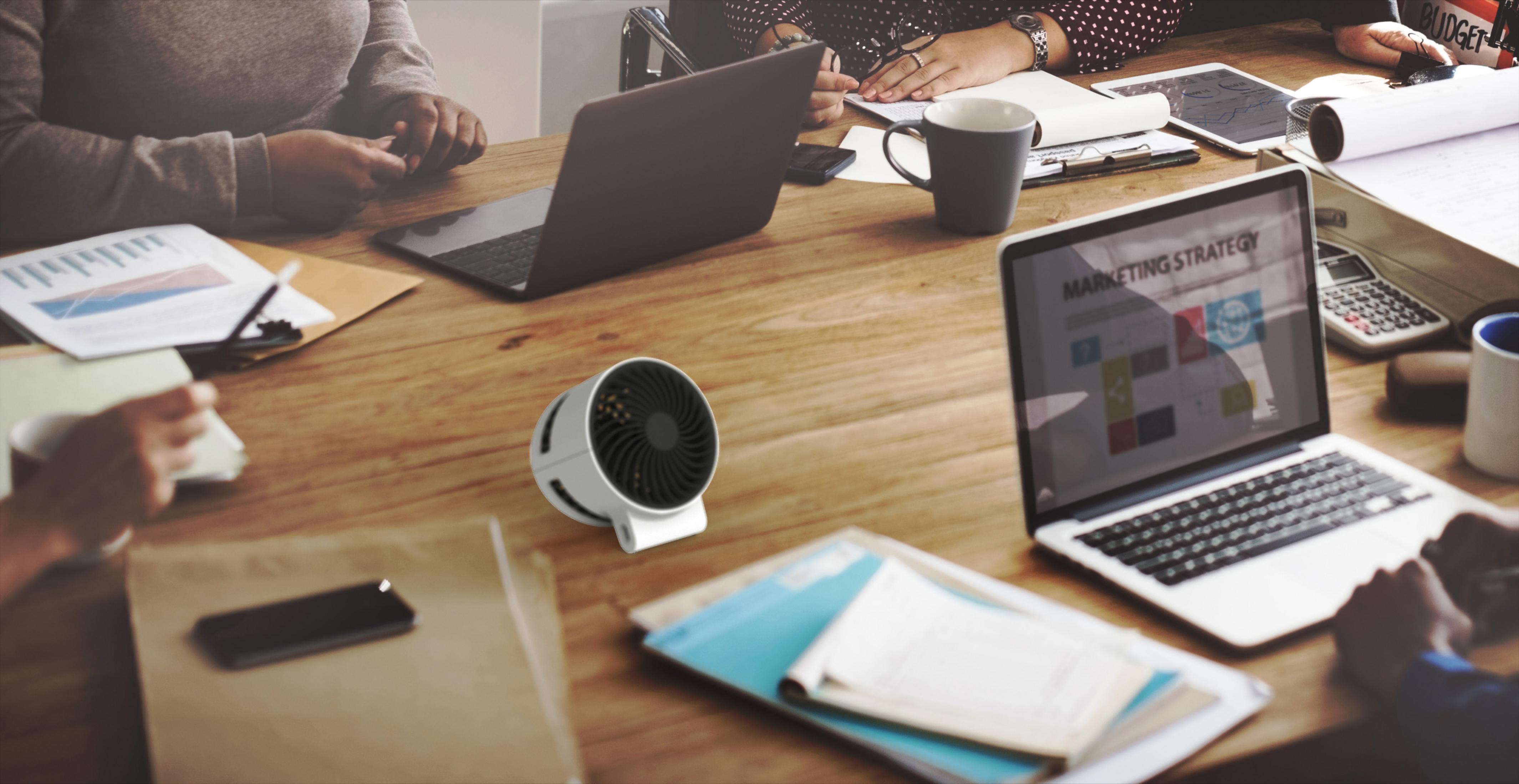 Ludzie na spotkaniu z laptopami, biały i czarny wentylator na biurku, drewniany stół.