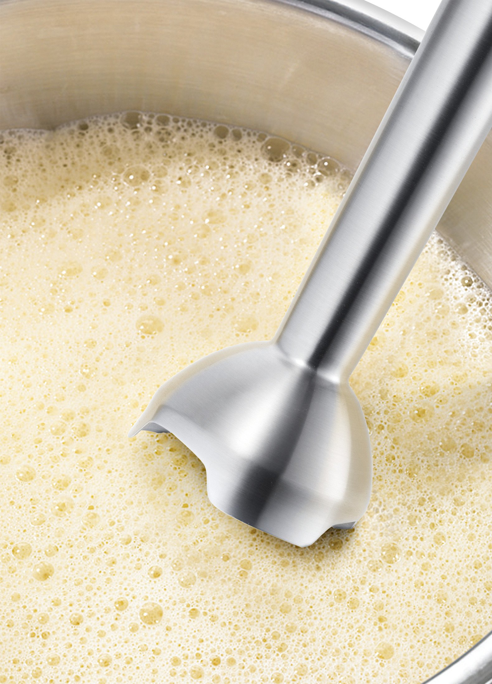 Gros plan d'un mixeur plongeant mélangeant un liquide dans une casserole.