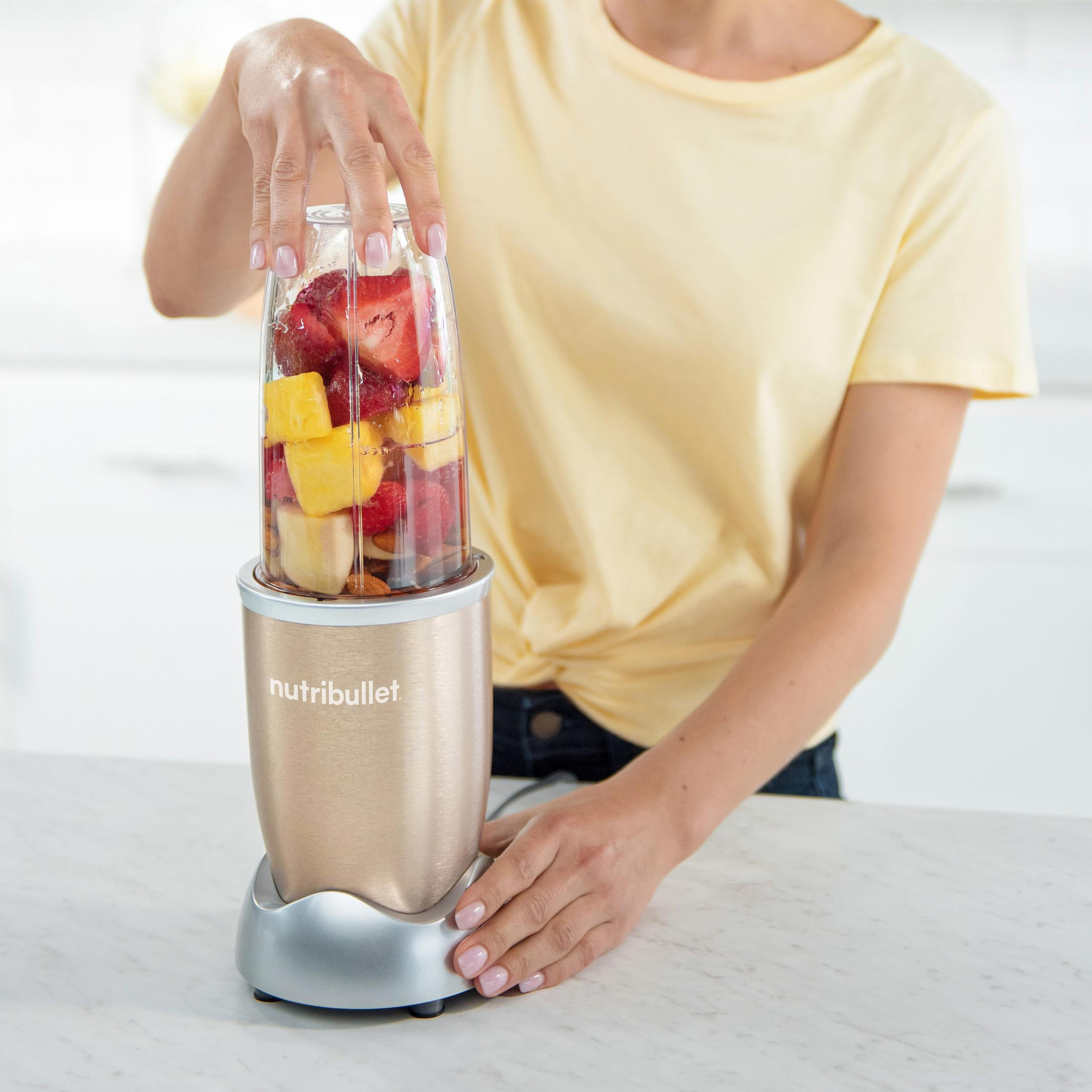 Eine Frau, die einen Smoothie in einem Nutribullet-Mixer zubereitet.