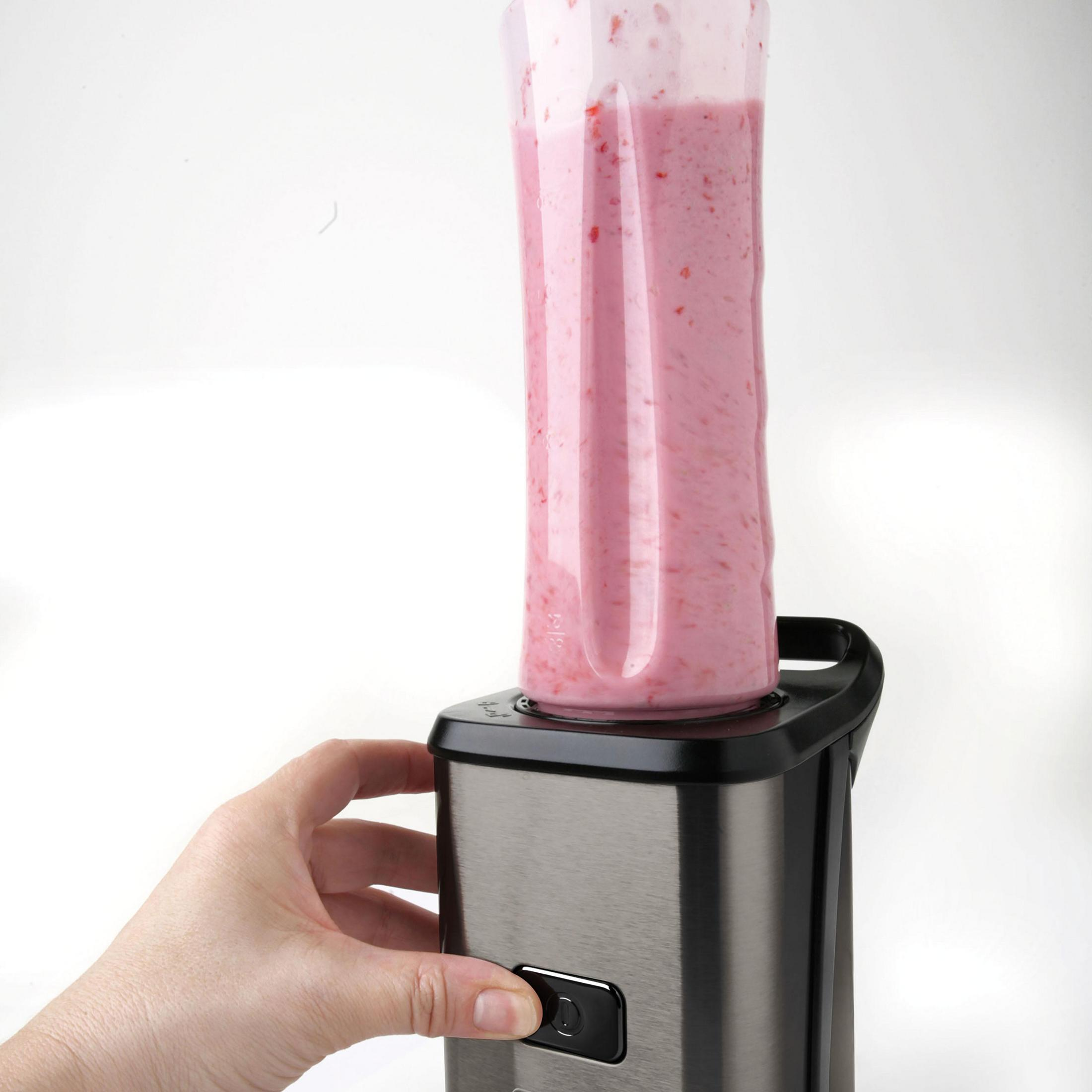 Ein Smoothie wird in einem Mixer gemixt. Eine Hand drückt einen Knopf.