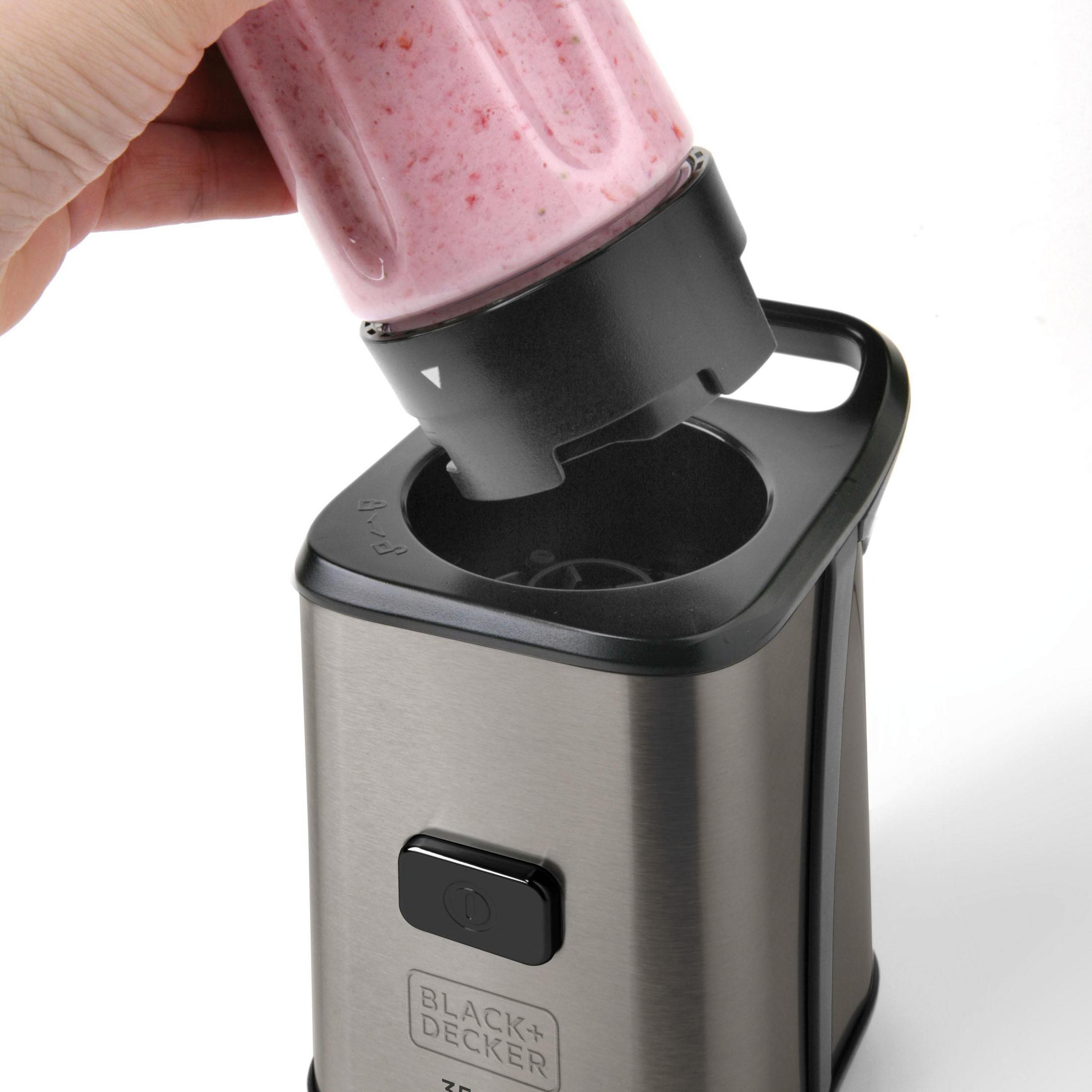 Eine Hand setzt einen Mixerbecher auf die Basis eines silber-schwarzen Mixers.