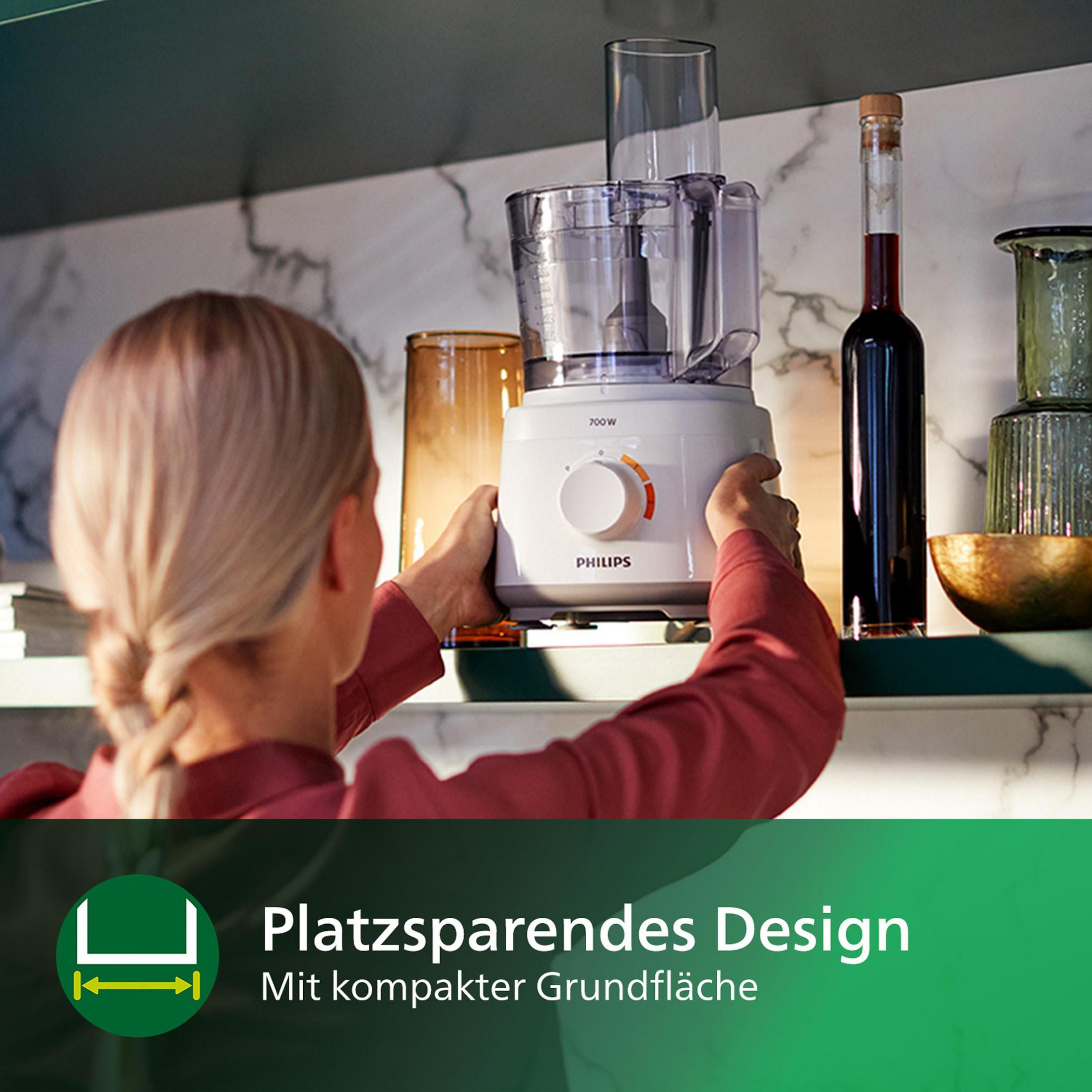 Person holding a food processor with a clear container on a shelf in a kitchen.