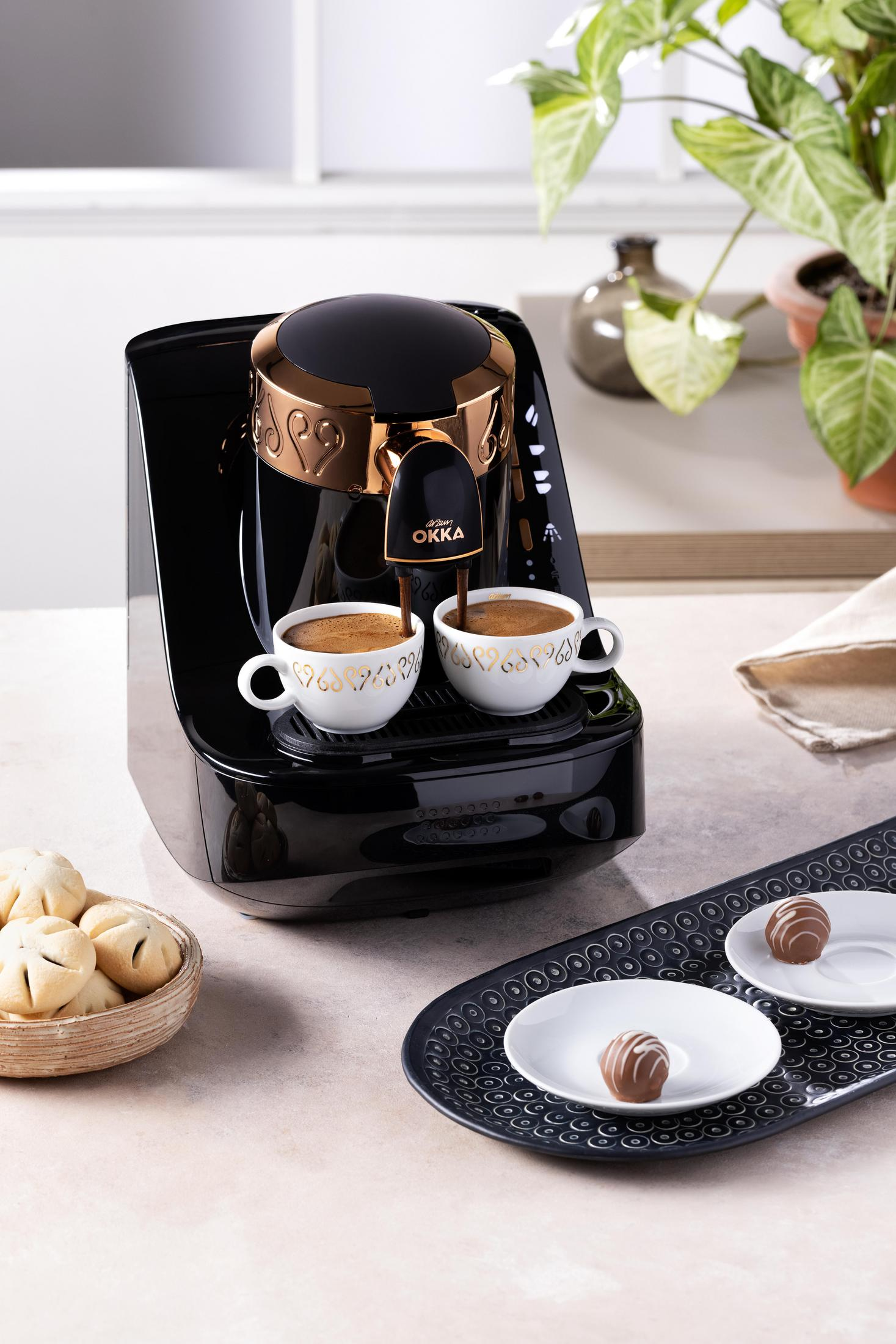 Kaffeemaschine, die Kaffee in zwei Tassen brüht. Kekse und Tablett daneben.