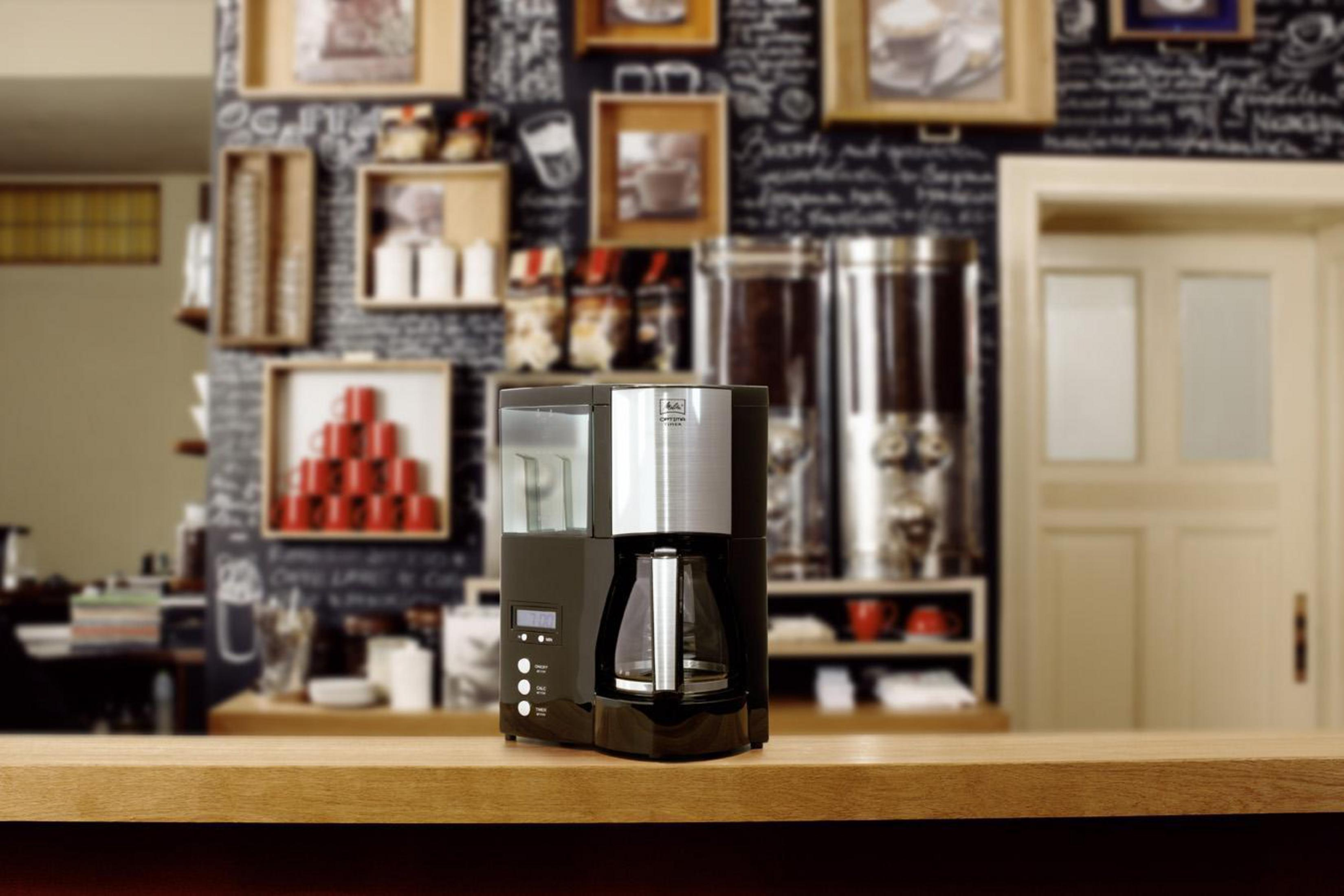 Ekspres do kawy na drewnianym blacie w kawiarni. Tło jest rozmyte z przedmiotami i ścianą.