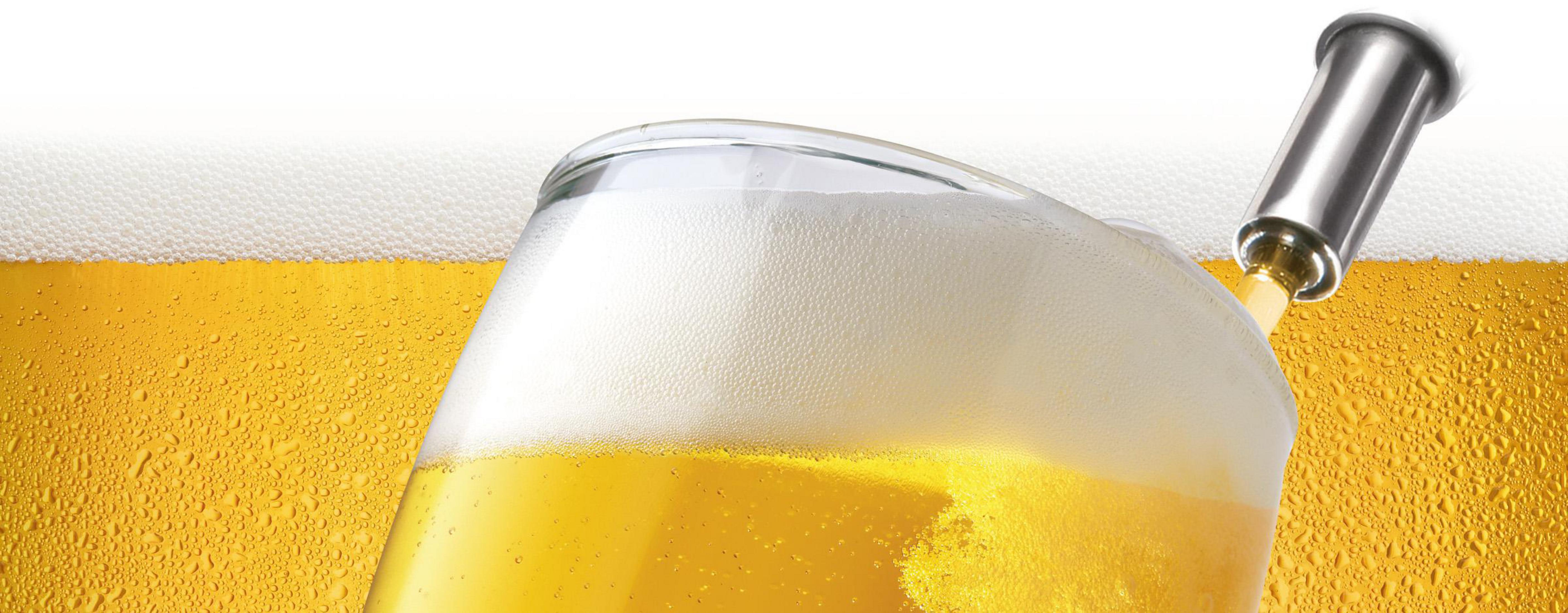 Un bicchiere di birra viene versato con un erogatore che ha un rubinetto d'argento. Lo sfondo è giallo.