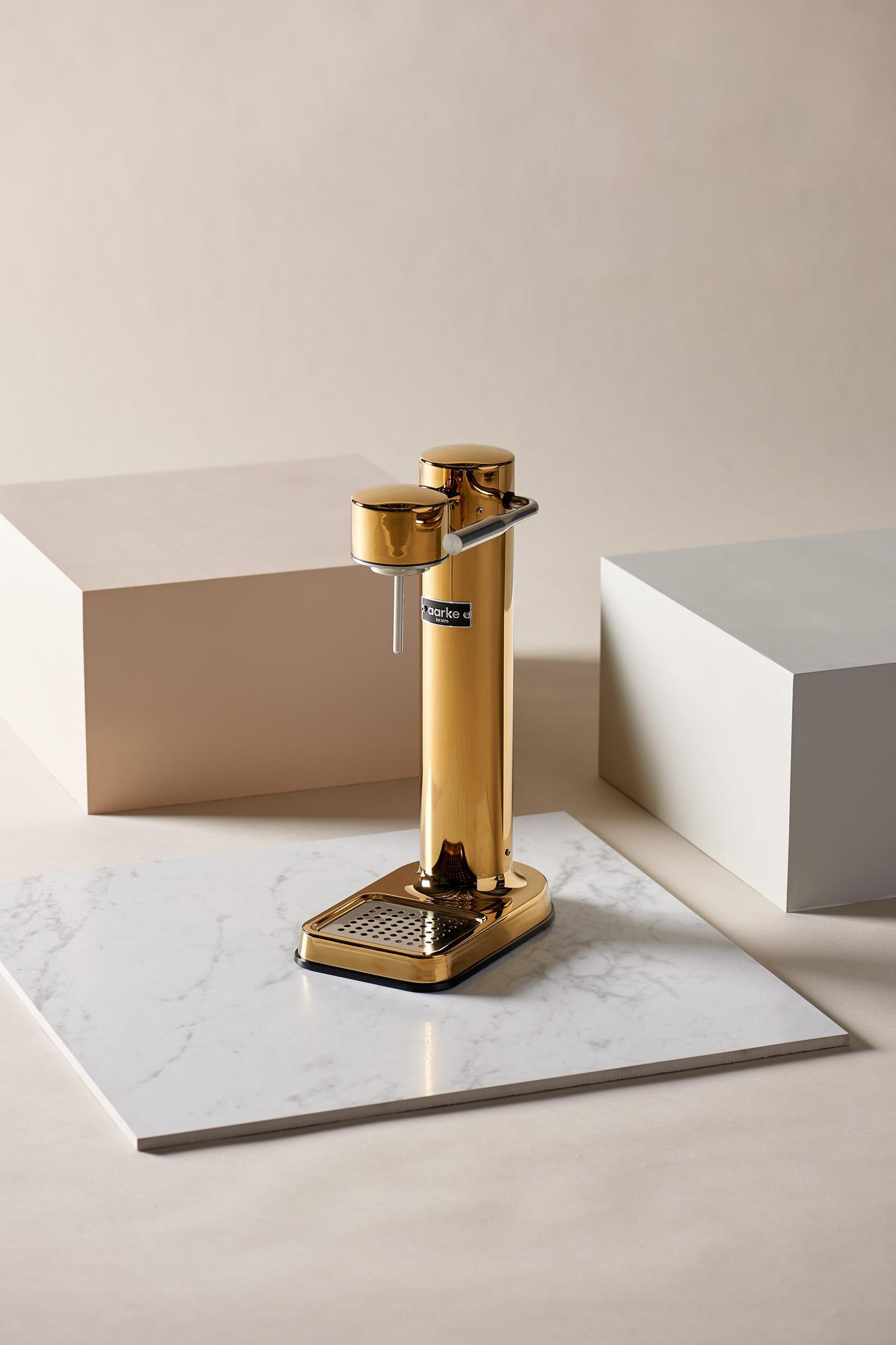 Sifone dorato su marmo, cubi beige sullo sfondo.