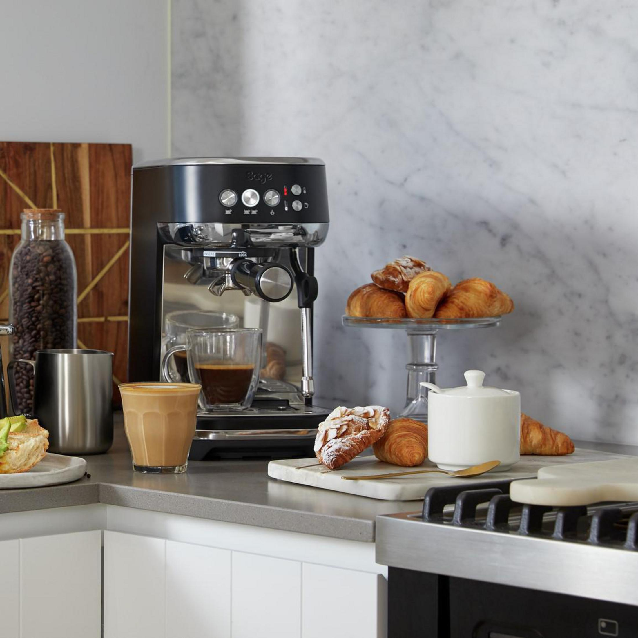 Scena kuchenna z ekspresem do kawy, rogalikami, kawą i innymi produktami śniadaniowymi.