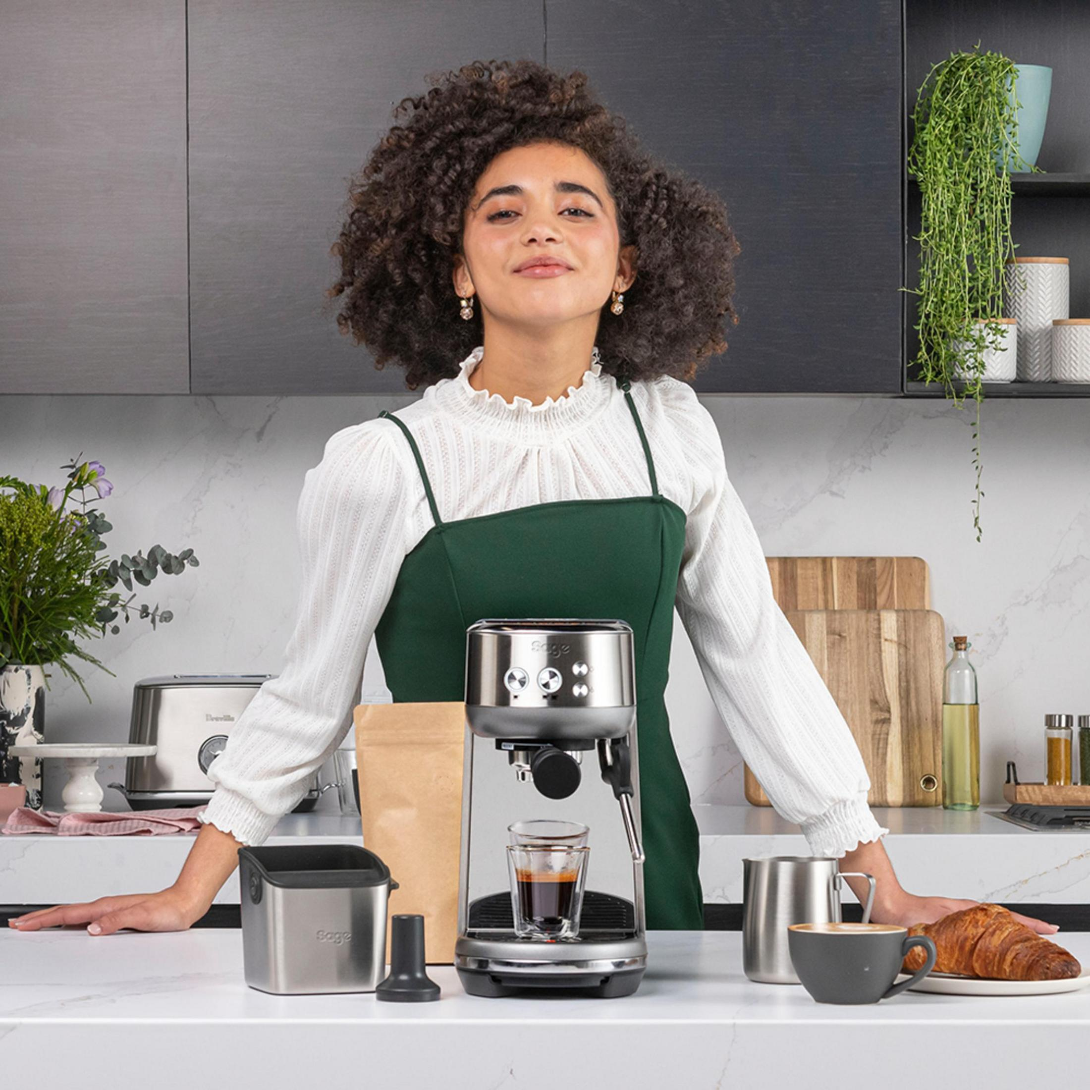 Vrouw met espressomachine. Inclusief kopje, koffie, croissant en accessoires.