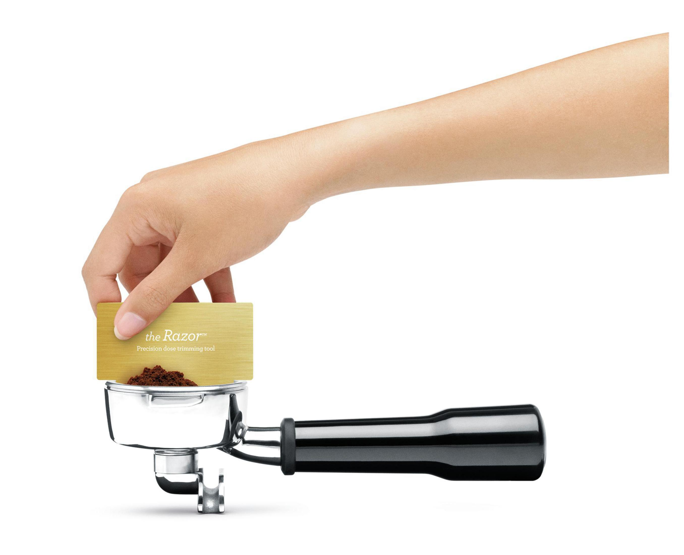 Hand hält goldenes Werkzeug über Kaffee-Siebträger. Das Werkzeug ist mit „the Razor“ beschriftet.