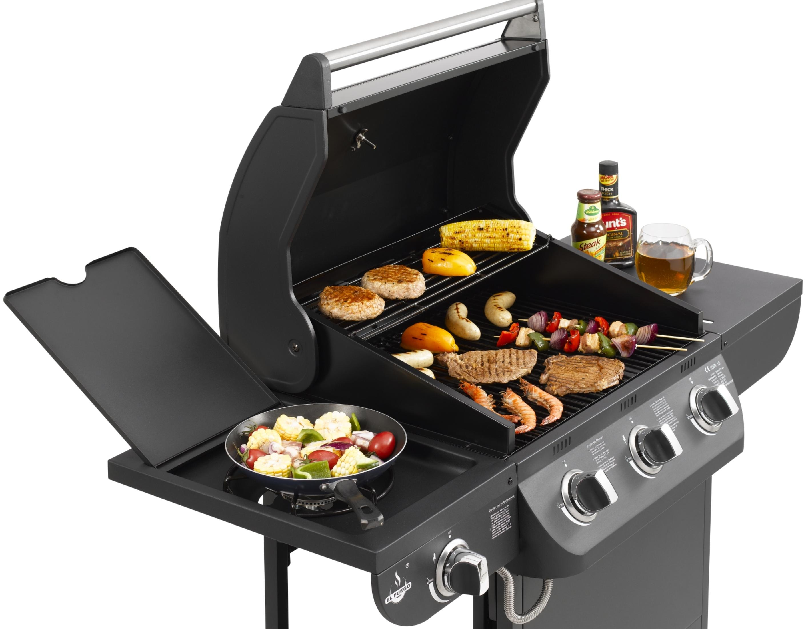 Ein schwarzer Grill mit verschiedenen Grillgerichten, Gewürzen und einem Bierkrug.