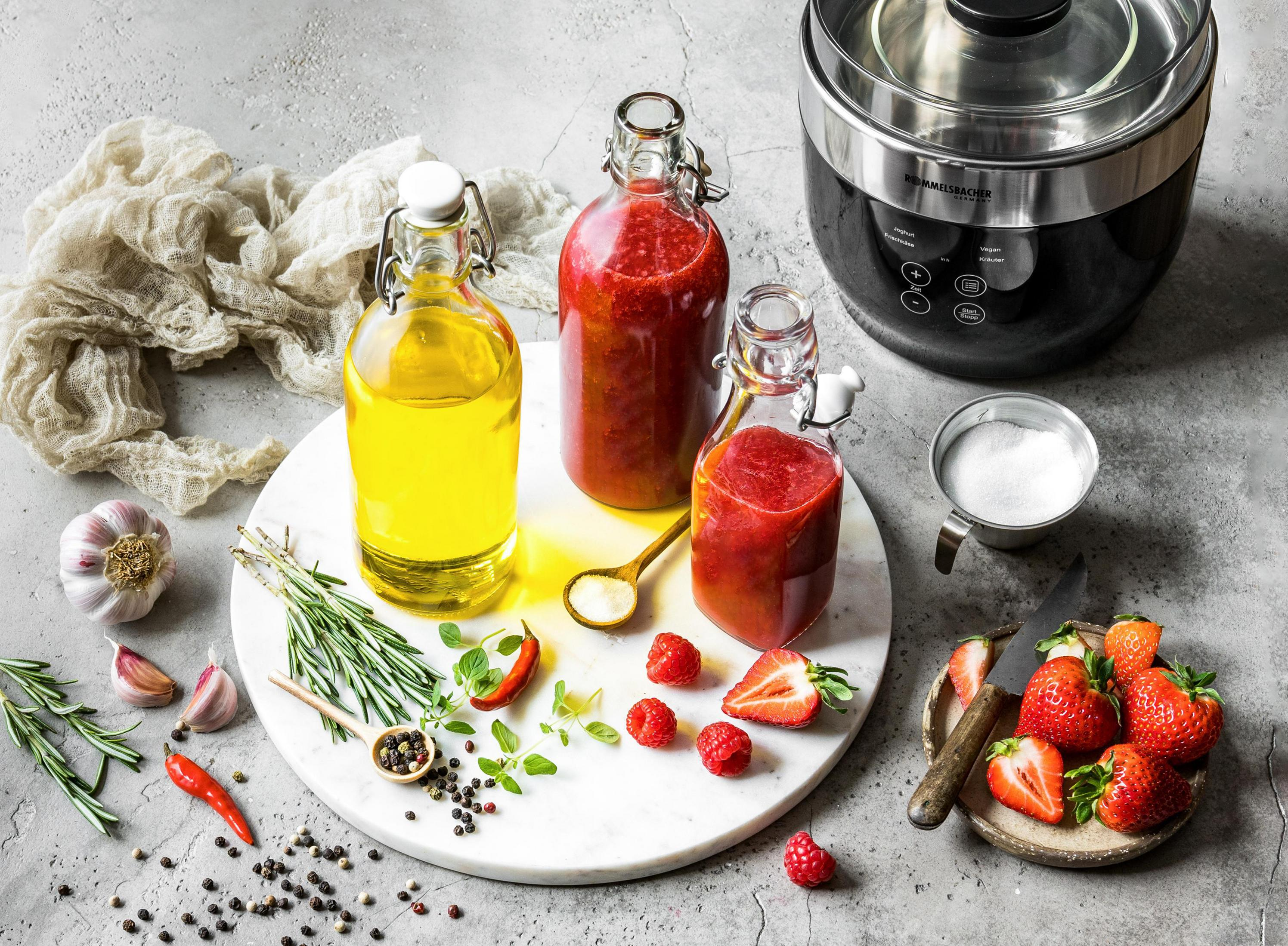 Marmoroberfläche mit Olivenöl, Erdbeersaft, Erdbeeren, Knoblauch und einem Foodprozessor.
