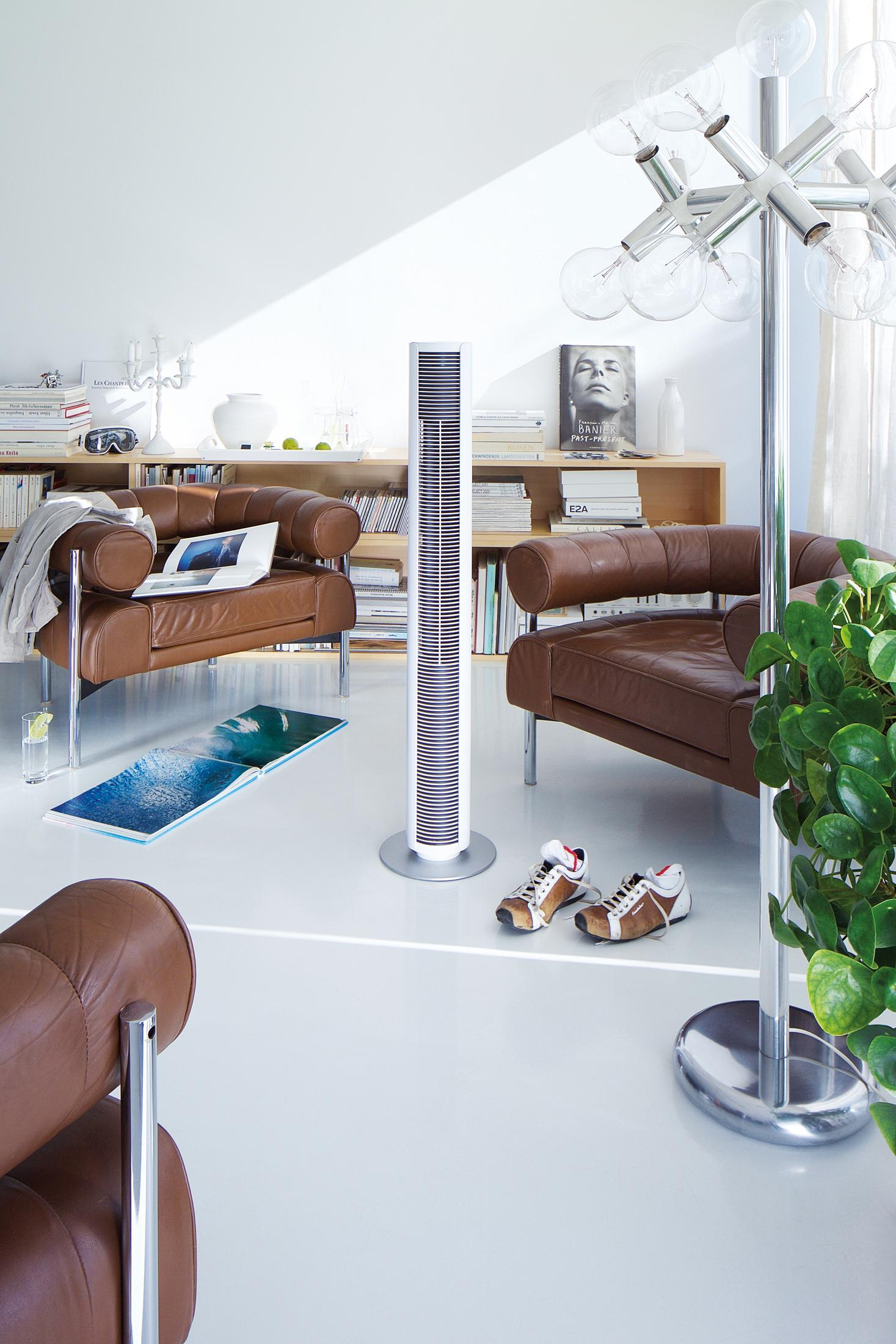 Un salon moderne avec des fauteuils en cuir marron et un grand ventilateur.
