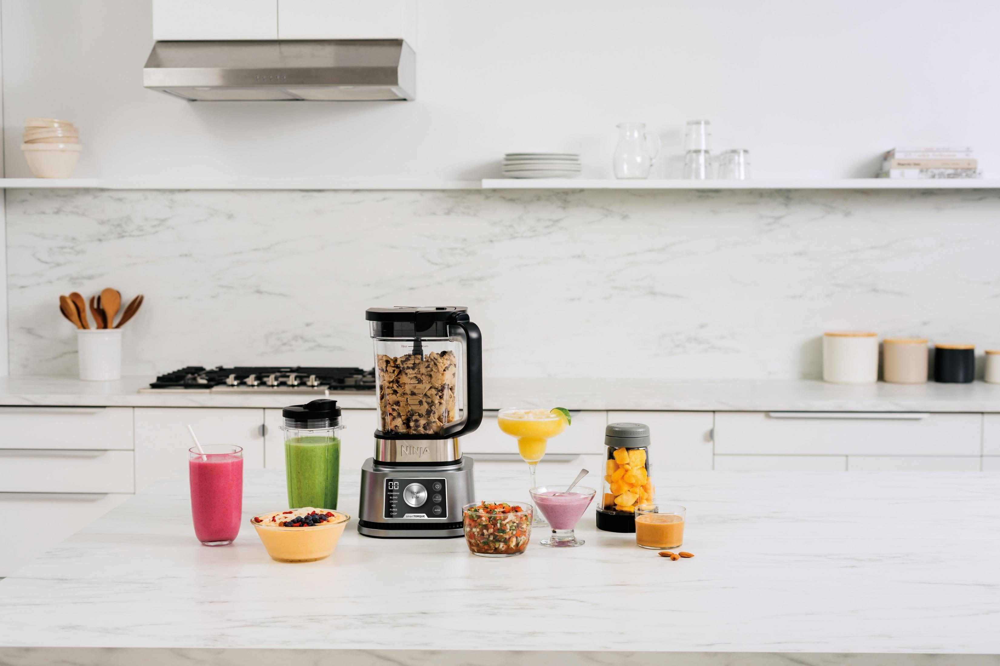 A kitchen scene with a blender and various prepared drinks and ingredients on a counter.
