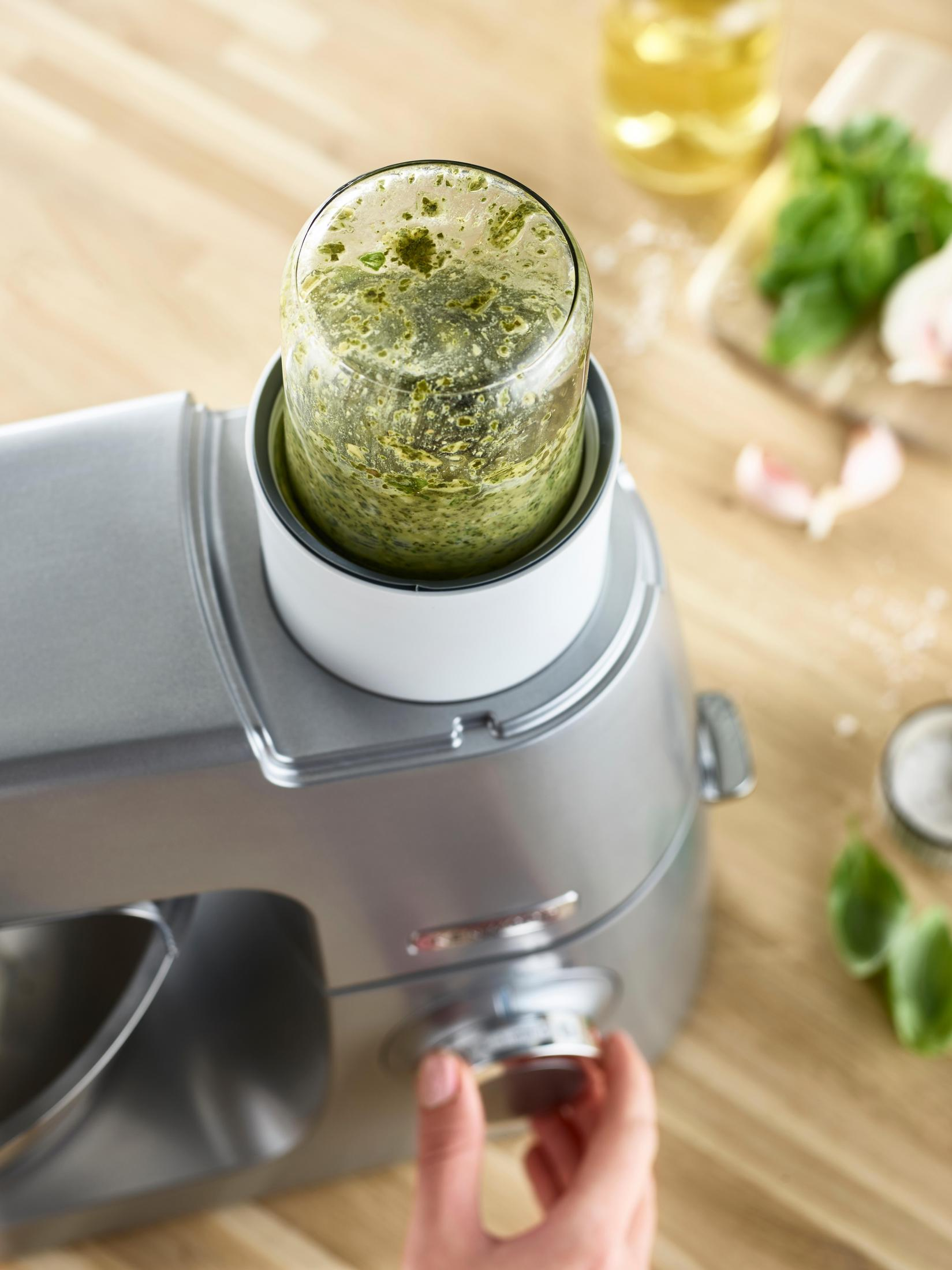 Robot kuchenny z pesto w środku, dłoń obracająca pokrętło.