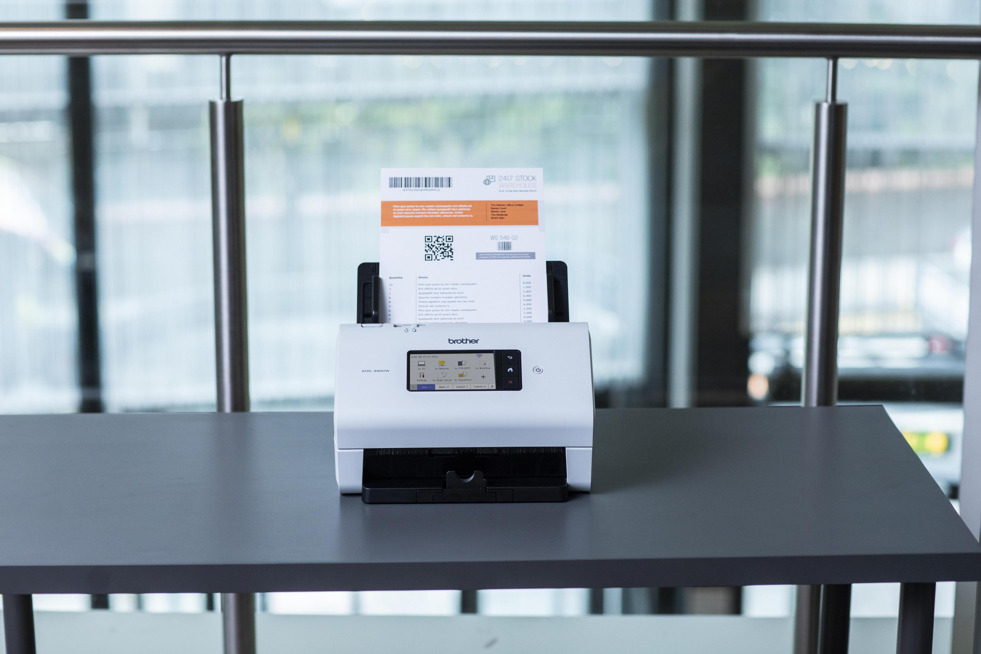 Biały skaner na szarym biurku, skanujący dokument z wydrukiem.