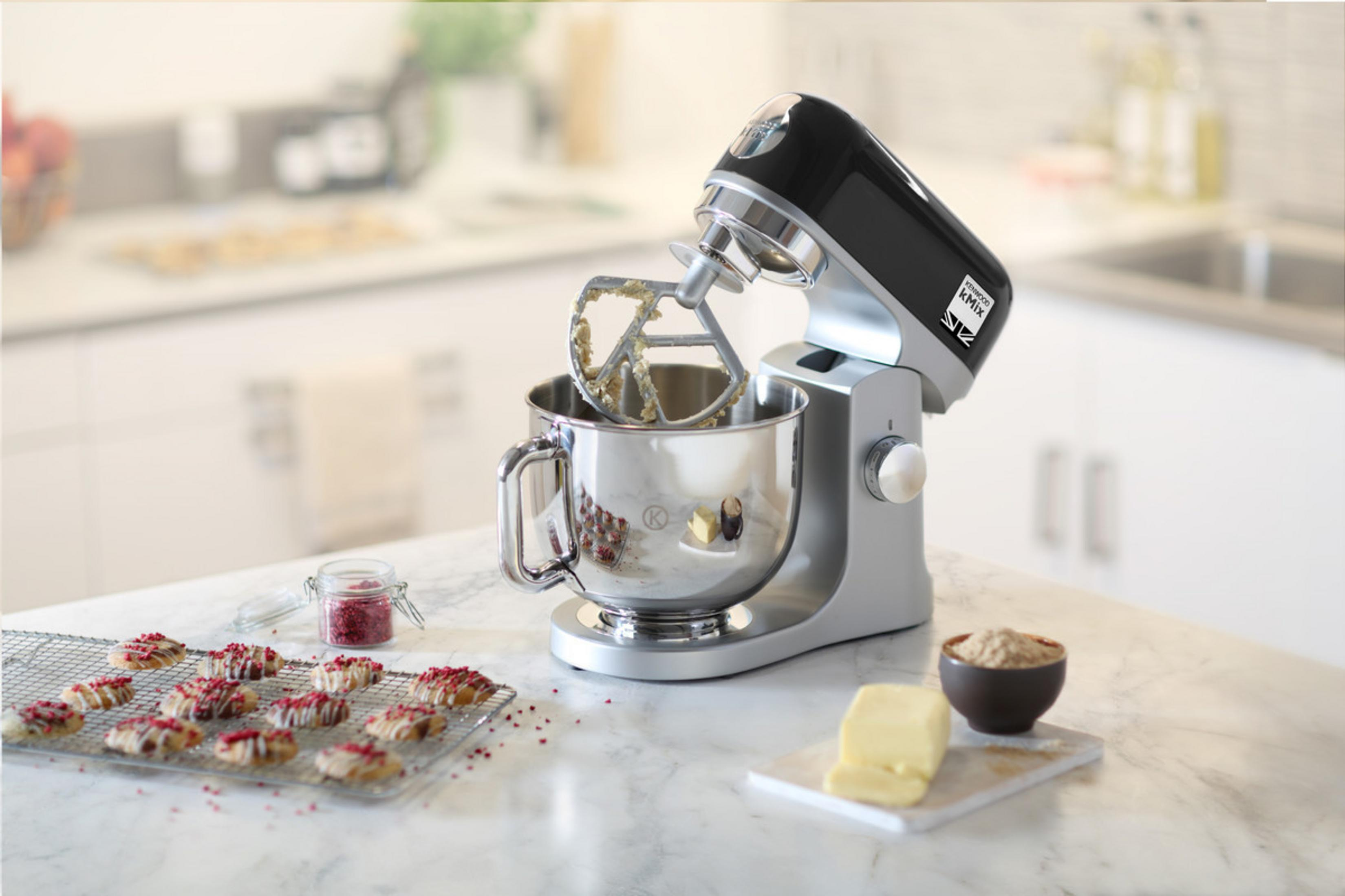 Küchenmixer mit Zutaten auf einem Tisch. Kekse auf einem Kühlgestell.