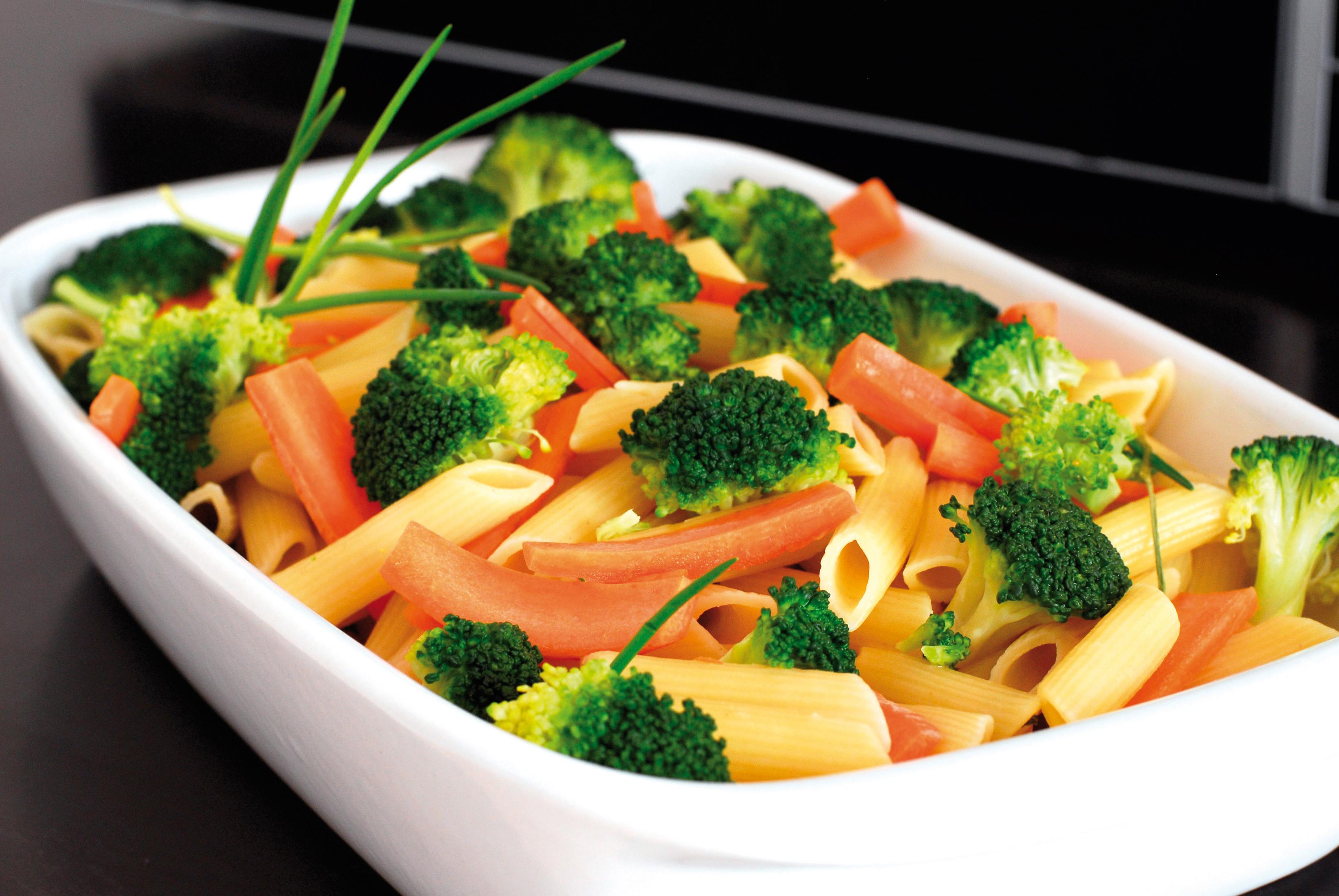 Pasta con broccoli e carote in un piatto bianco, un pasto sano.